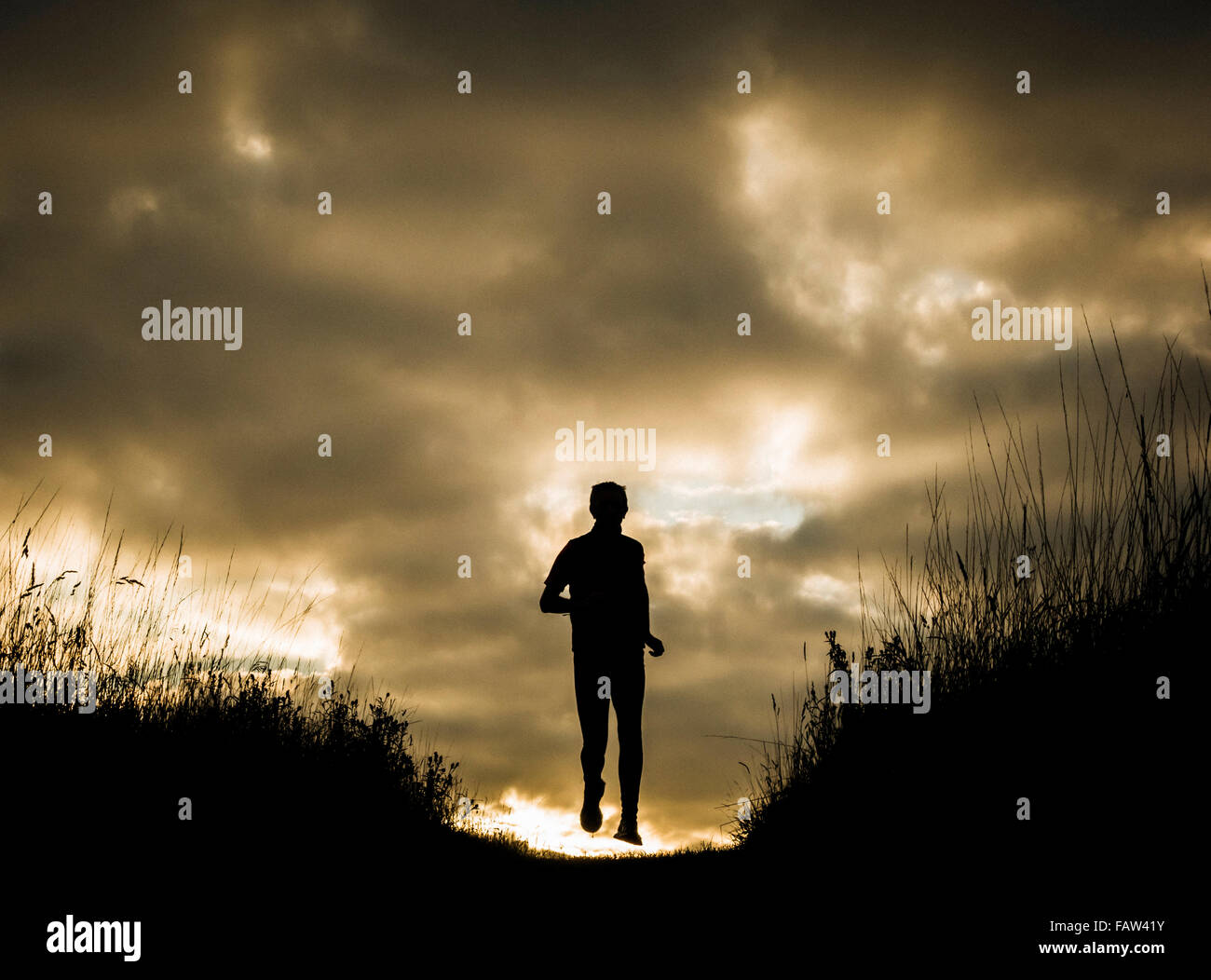 Silhouette d'homme jogger sur hill au lever du soleil. UK Banque D'Images