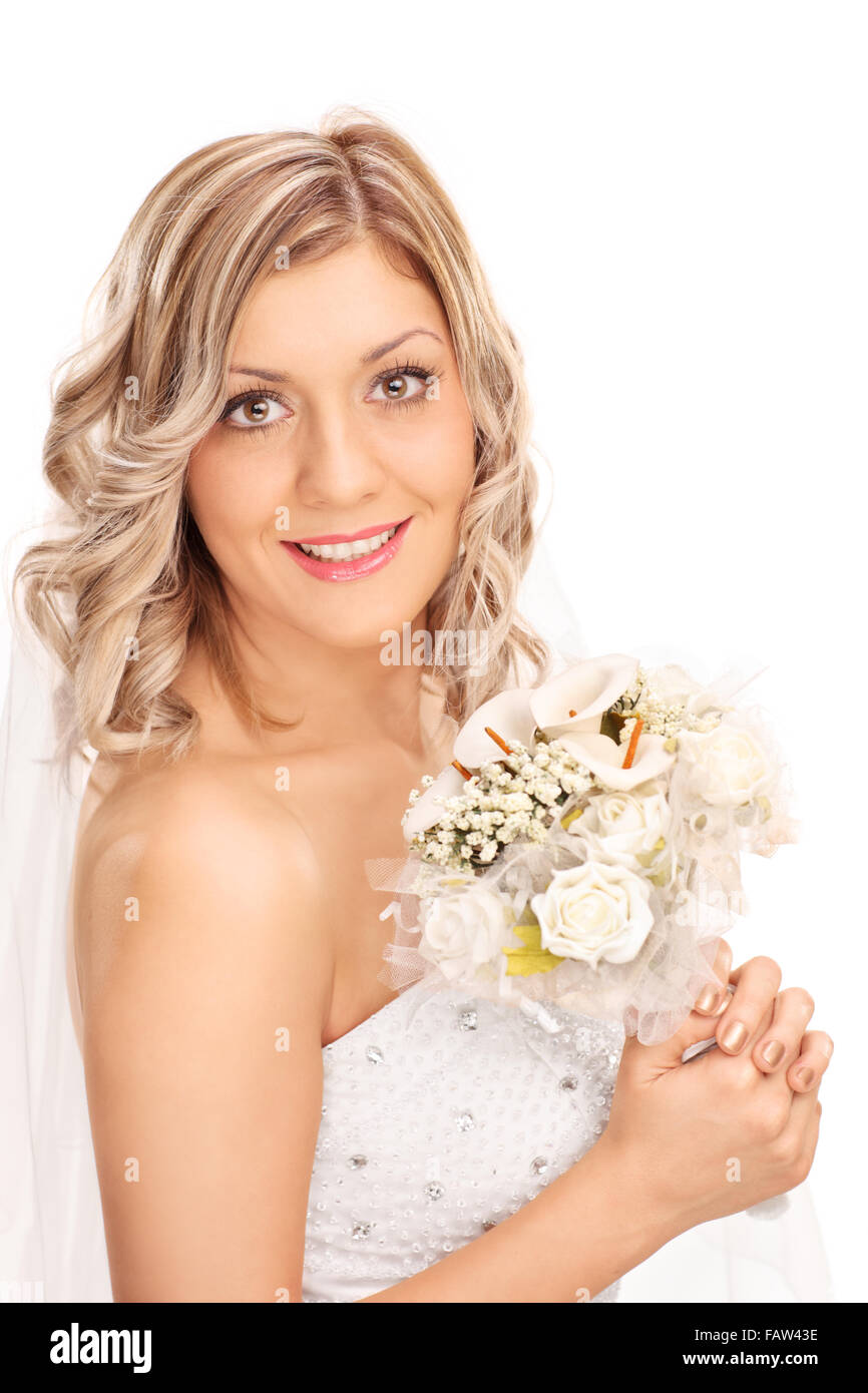 Shot verticale d'une jeune blonde bride tenant une fleur de mariage et posant dans une robe de mariée blanche isolé sur fond blanc Banque D'Images