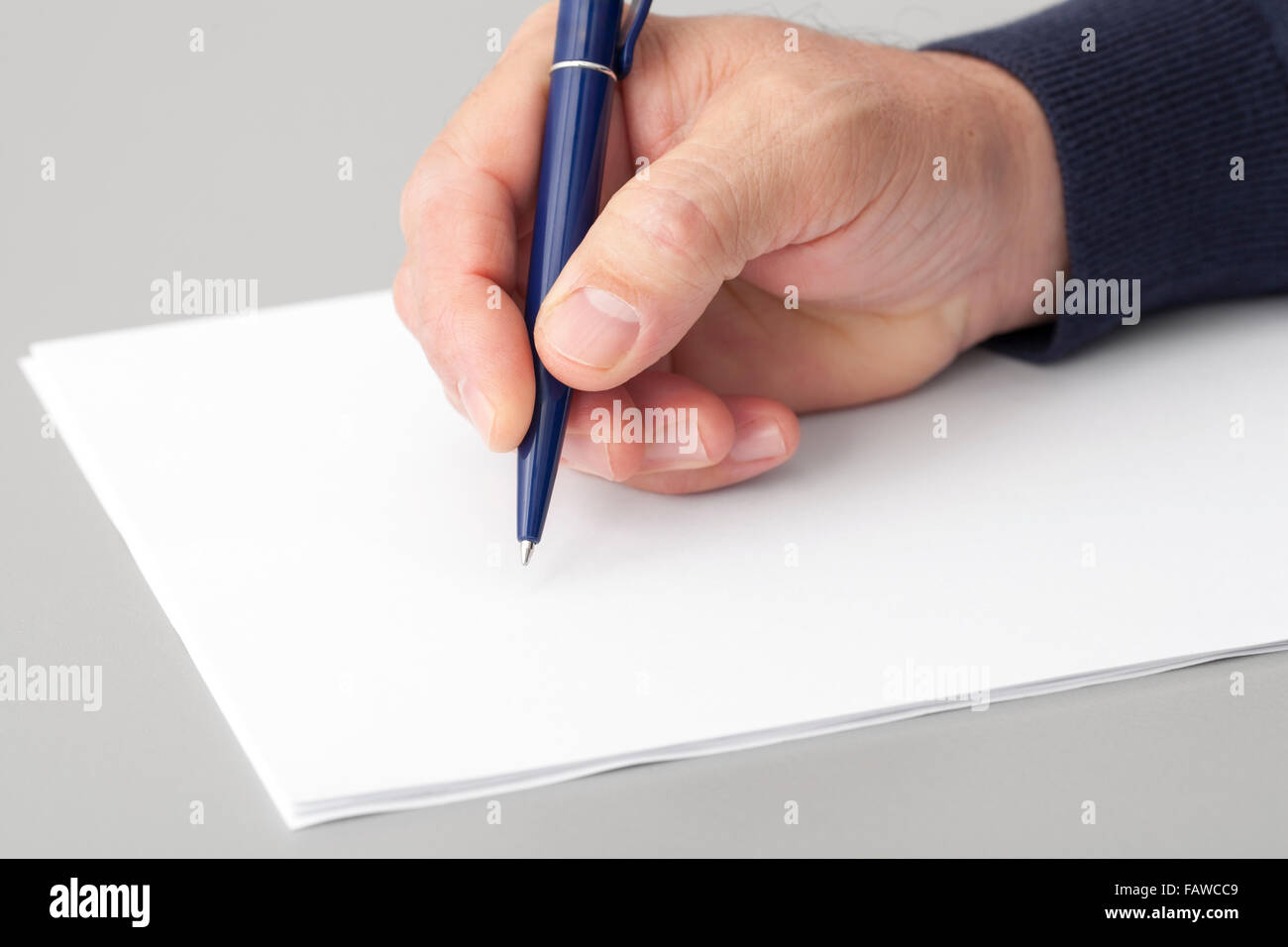 La main de l'écriture avec un stylo sur un livre blanc des draps propres. Banque D'Images