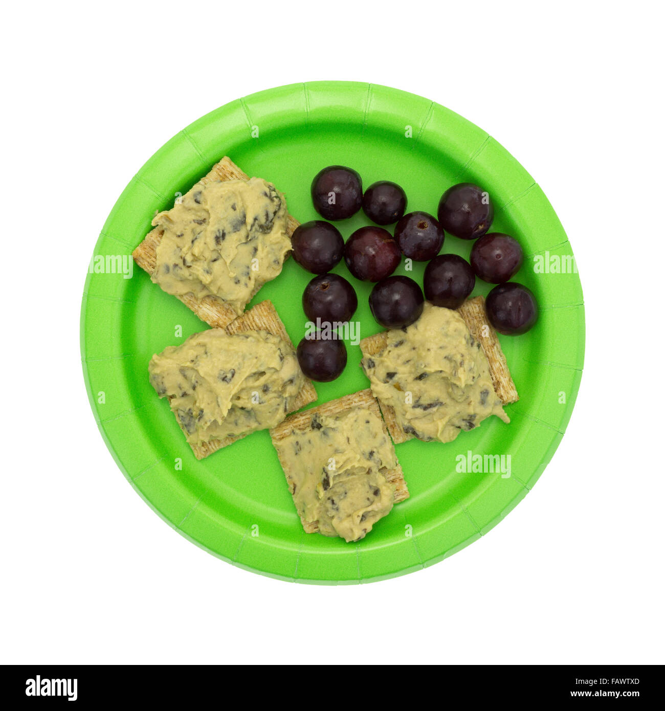 Vue de dessus d'un régime alimentaire de plusieurs repas épinards hommus sur craquelins à grains entiers avec des raisins sur une assiette en papier vert Banque D'Images