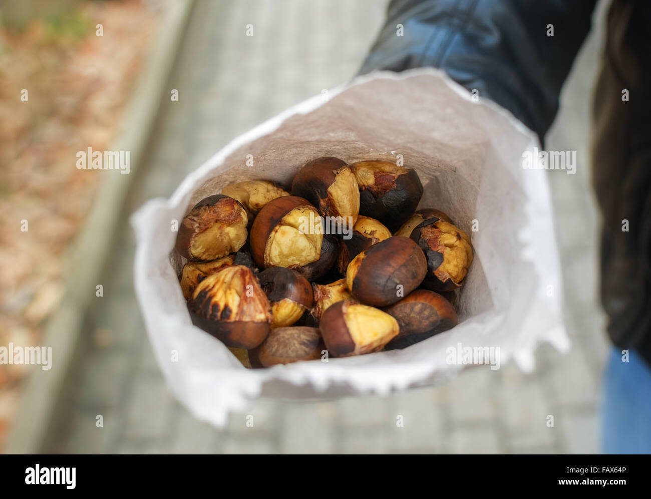 Man holding fresh châtaignes grillées en sac de papier. Banque D'Images