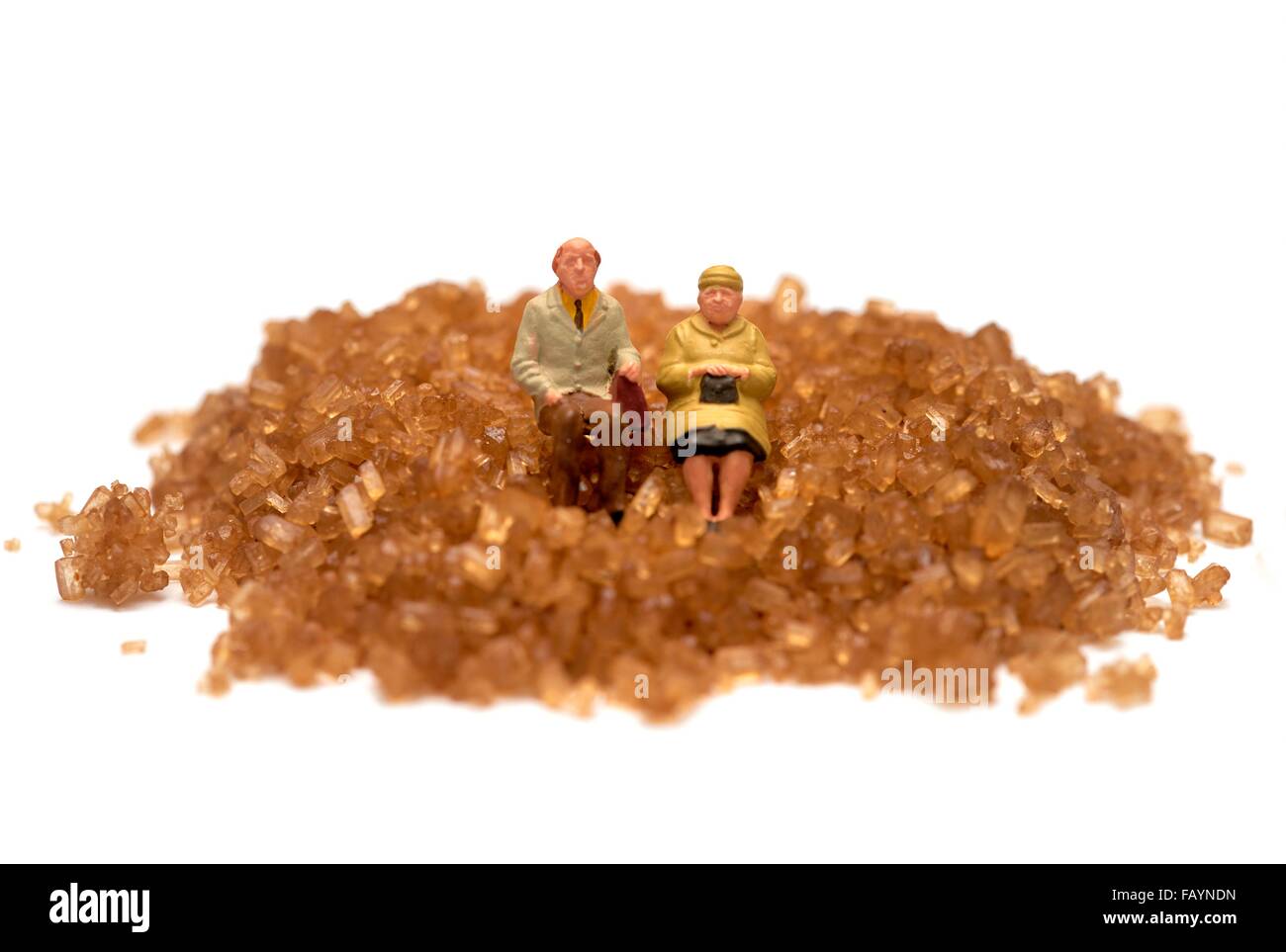 Les gens miniature assis sur un tas de sucre brun concept diabète Banque D'Images