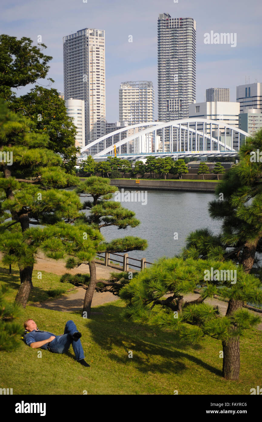 Garçon couché sur l'herbe à Hama Rikyu Gardens Tokyo Japon Banque D'Images