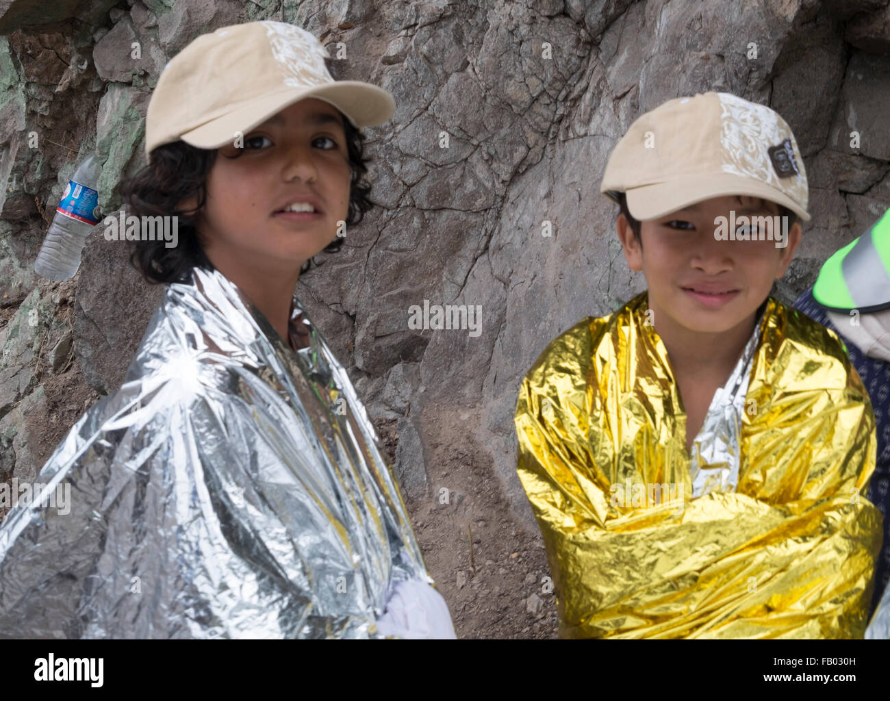 Deux enfants réfugiés afghans sourire alors qu'ils se chauffer dans un chapeau et des couvertures après la traversée de la Turquie à Lesbos, Grèce. Banque D'Images
