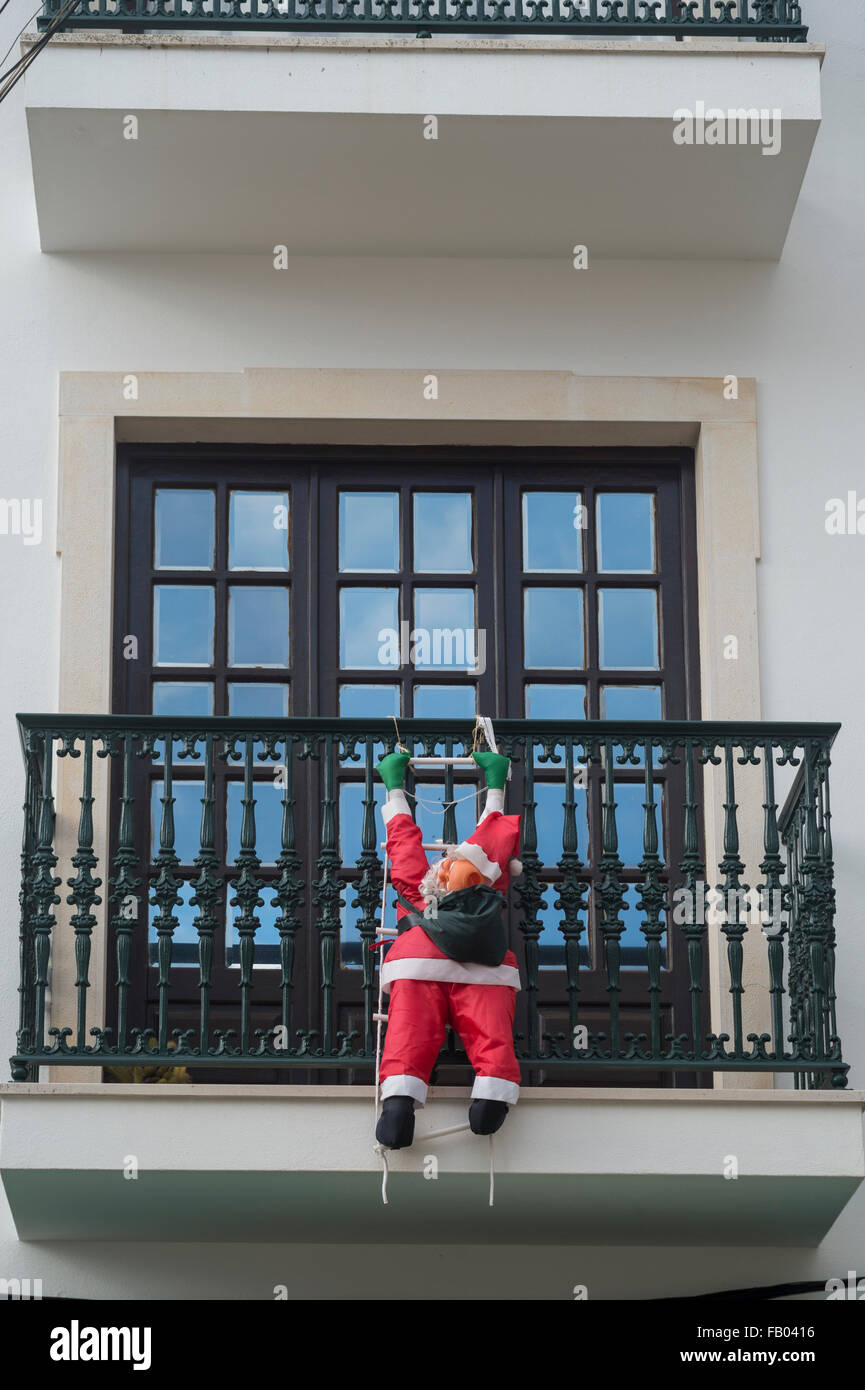 Père Noël gonflable grimper un balcon sur un immeuble. Banque D'Images