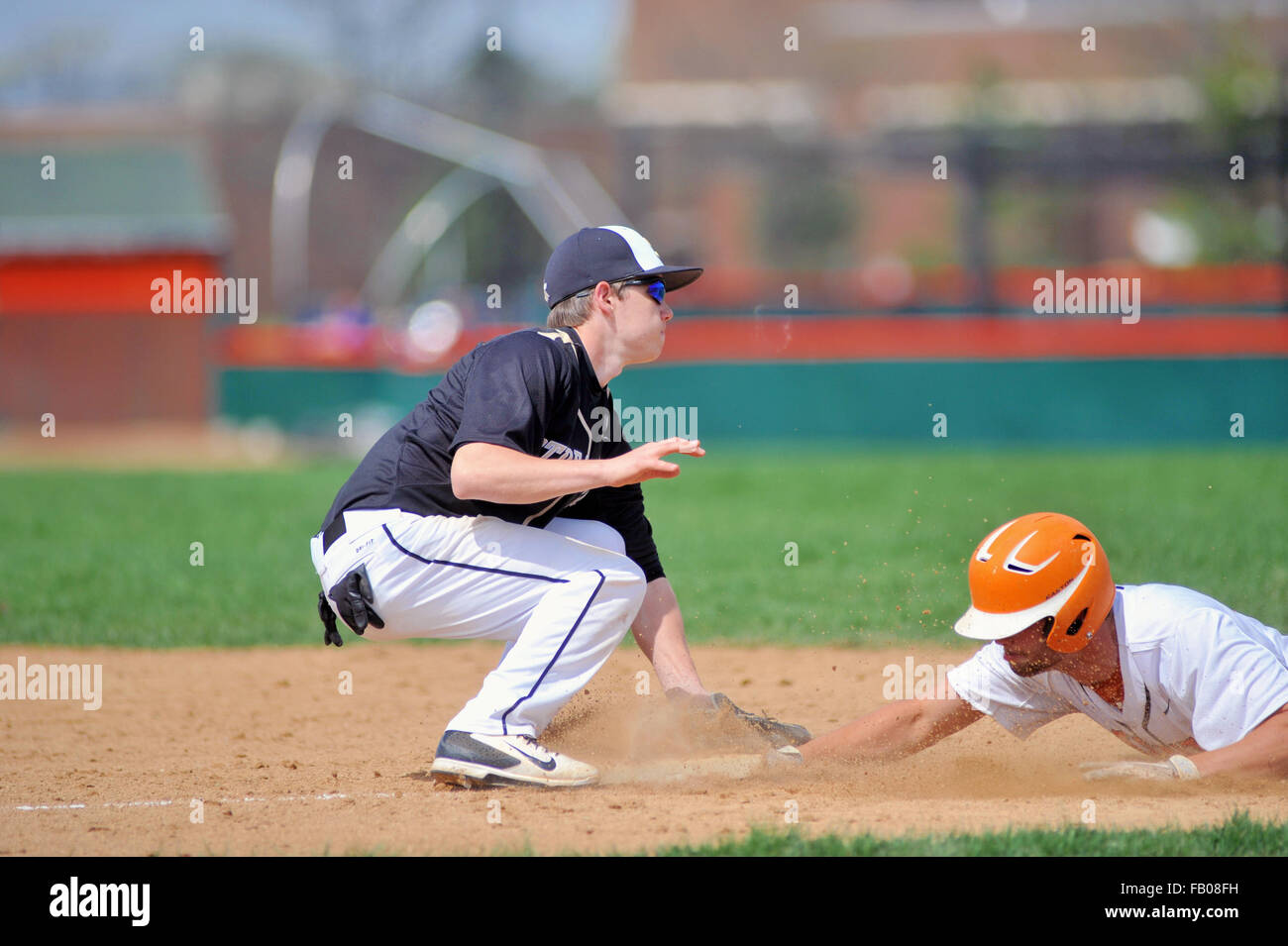 Troisième but applique un tag sur un bloc coulissant sur un pickoff jouer à la troisième base durant un match de baseball de l'école secondaire. USA. Banque D'Images