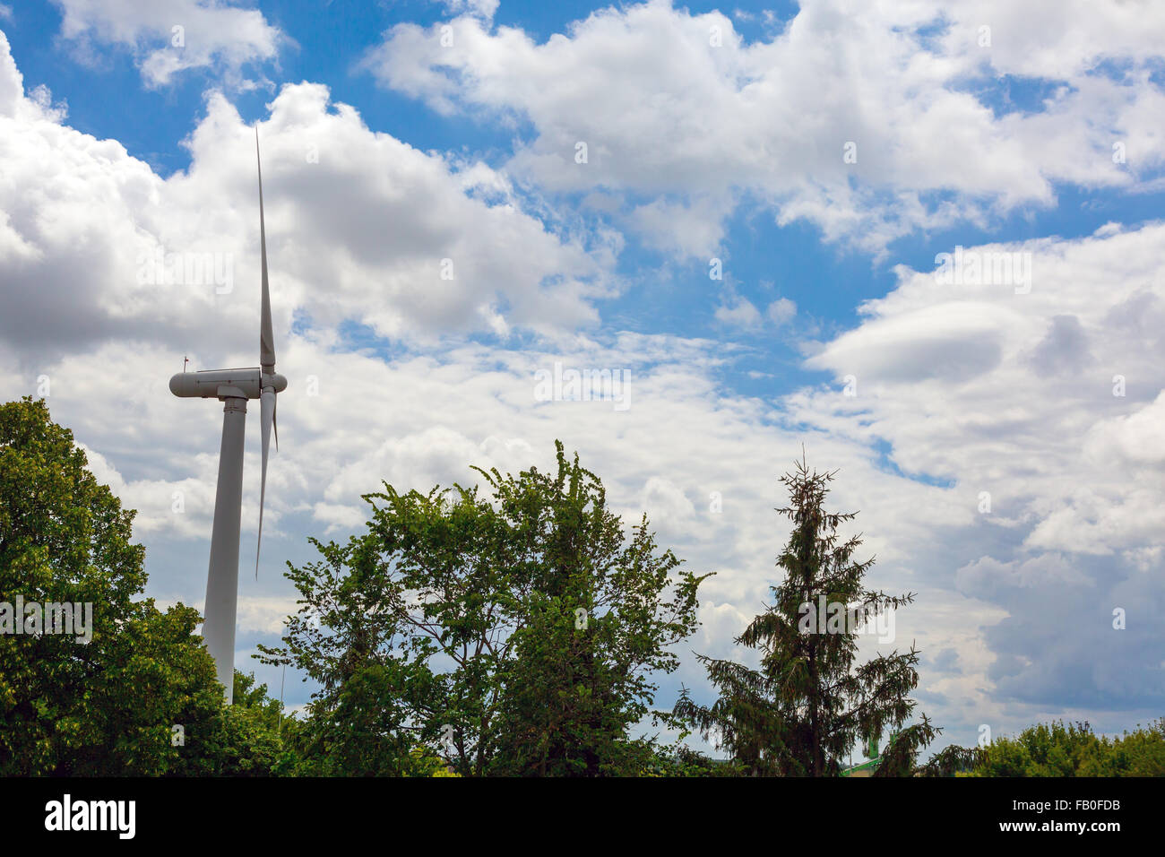 Générateur d'énergie éolienne avec lames en rotation sur ciel bleu nuage spectaculaire massif extérieur lumière du jour Banque D'Images