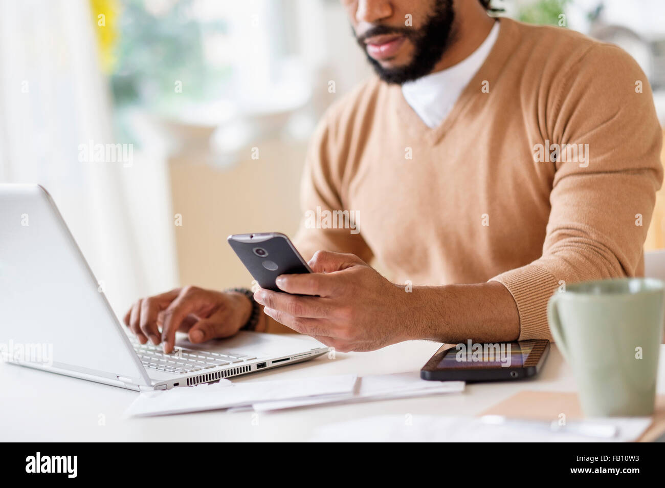 L'homme travaillant avec laptop et holding smart phone Banque D'Images