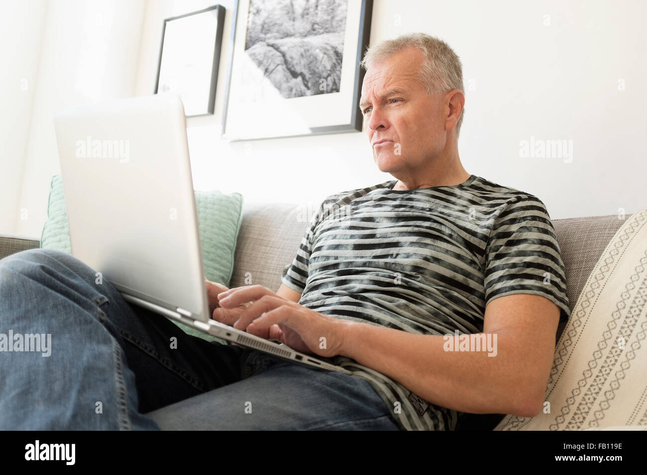 Man sitting on sofa using laptop Banque D'Images