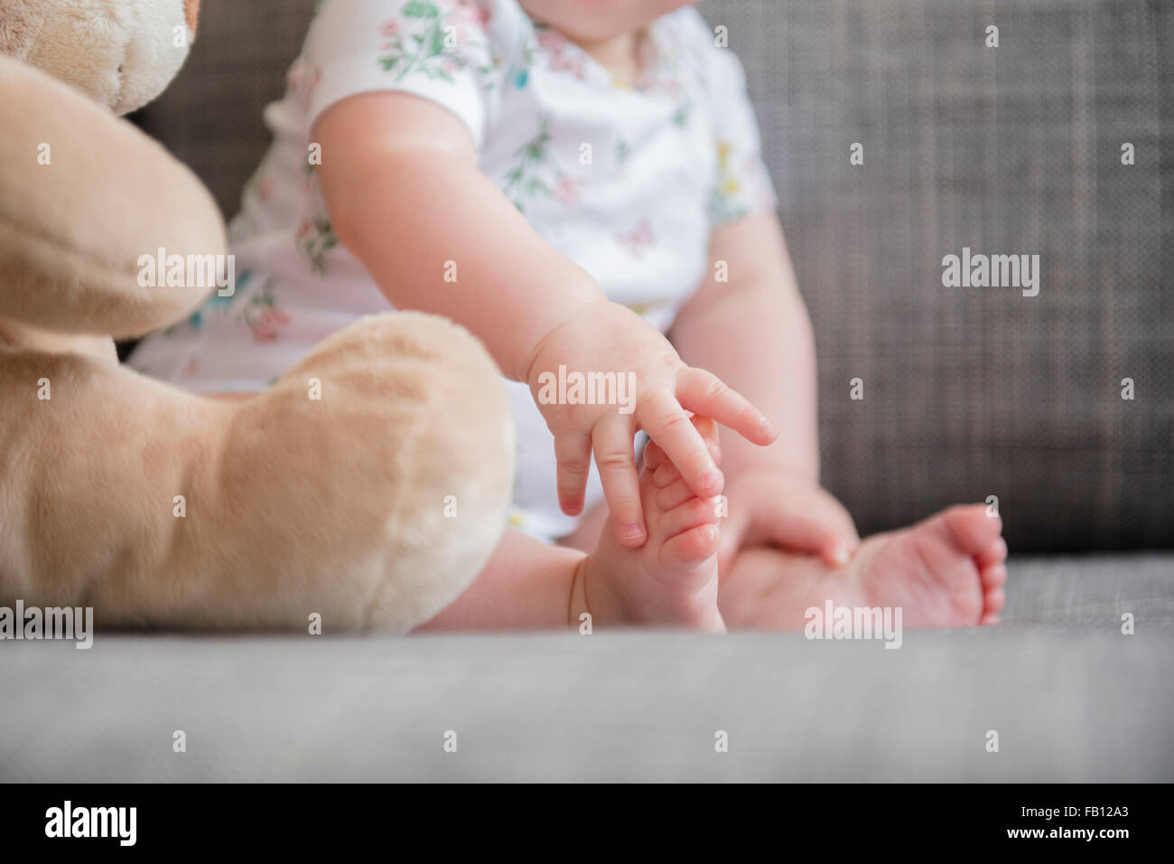 Baby Girl (4-5) holding foot Banque D'Images