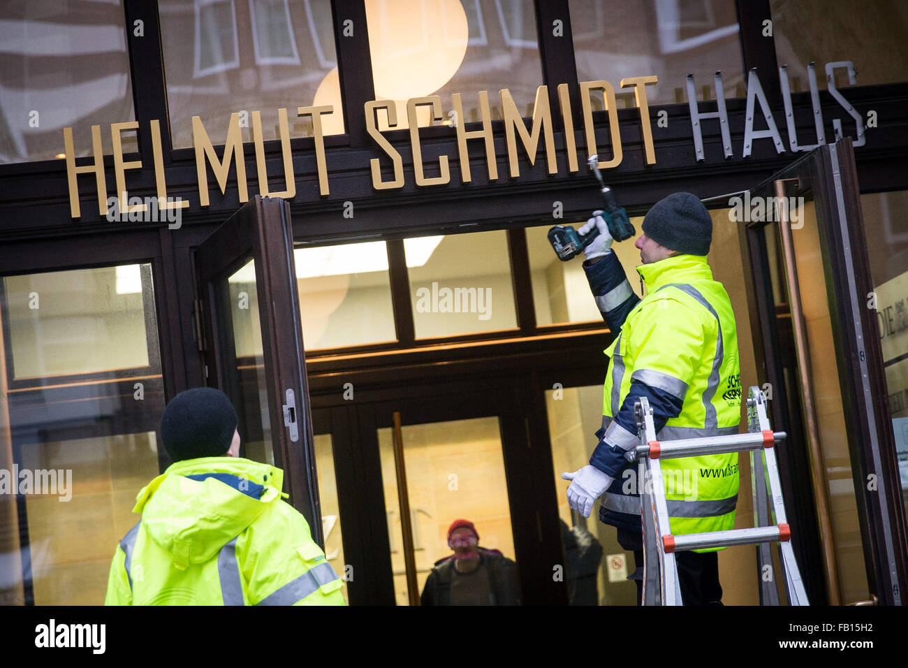 Hambourg, Allemagne. Jan 7, 2016. Les hommes définir la nouvelle 'lettrage Helmut-Schmidt-Haus' sur l'entrée de l'immeuble anciennement connu sous le nom de 'Pressehaus' dans le centre de Hambourg, Allemagne, 7 janvier 2016. La maison d'édition de l'hebdomadaire Die Zeit est en train de changer son nom en l'honneur de l'éditeur de longue date et l'ancien chancelier allemand Helmut Schmidt (1918-2015). PHOTO : CHRISTIAN CHARISIUS/DPA/Alamy Live News Banque D'Images