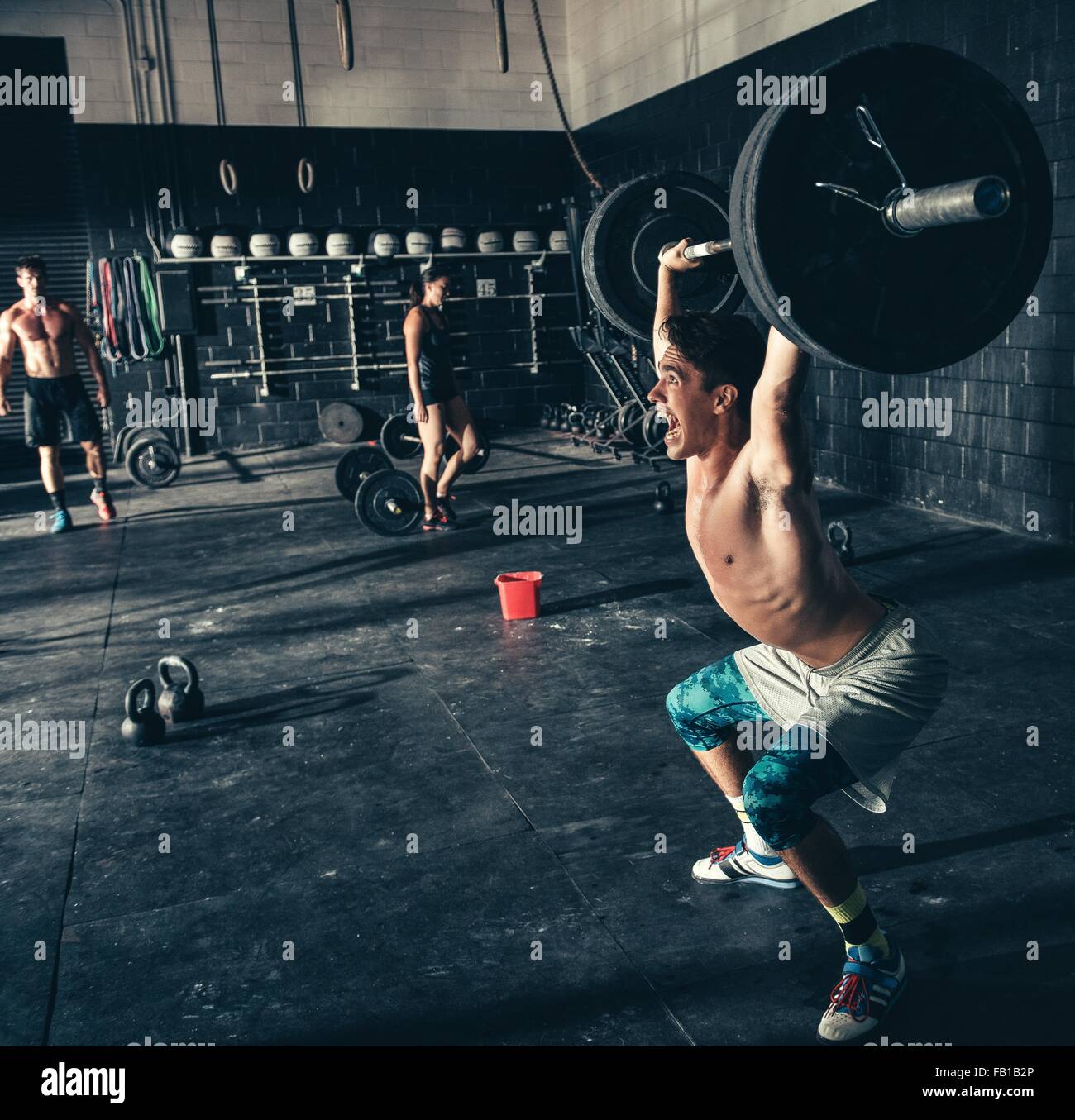 L'homme criant tout en soulevant en Haltères fitness Banque D'Images