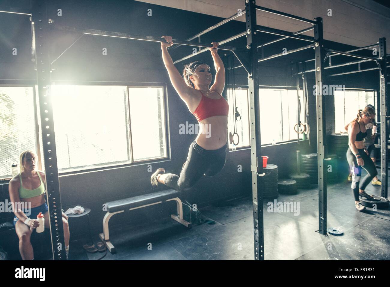 Woman swinging sur barre d'exercice dans la salle de sport Banque D'Images
