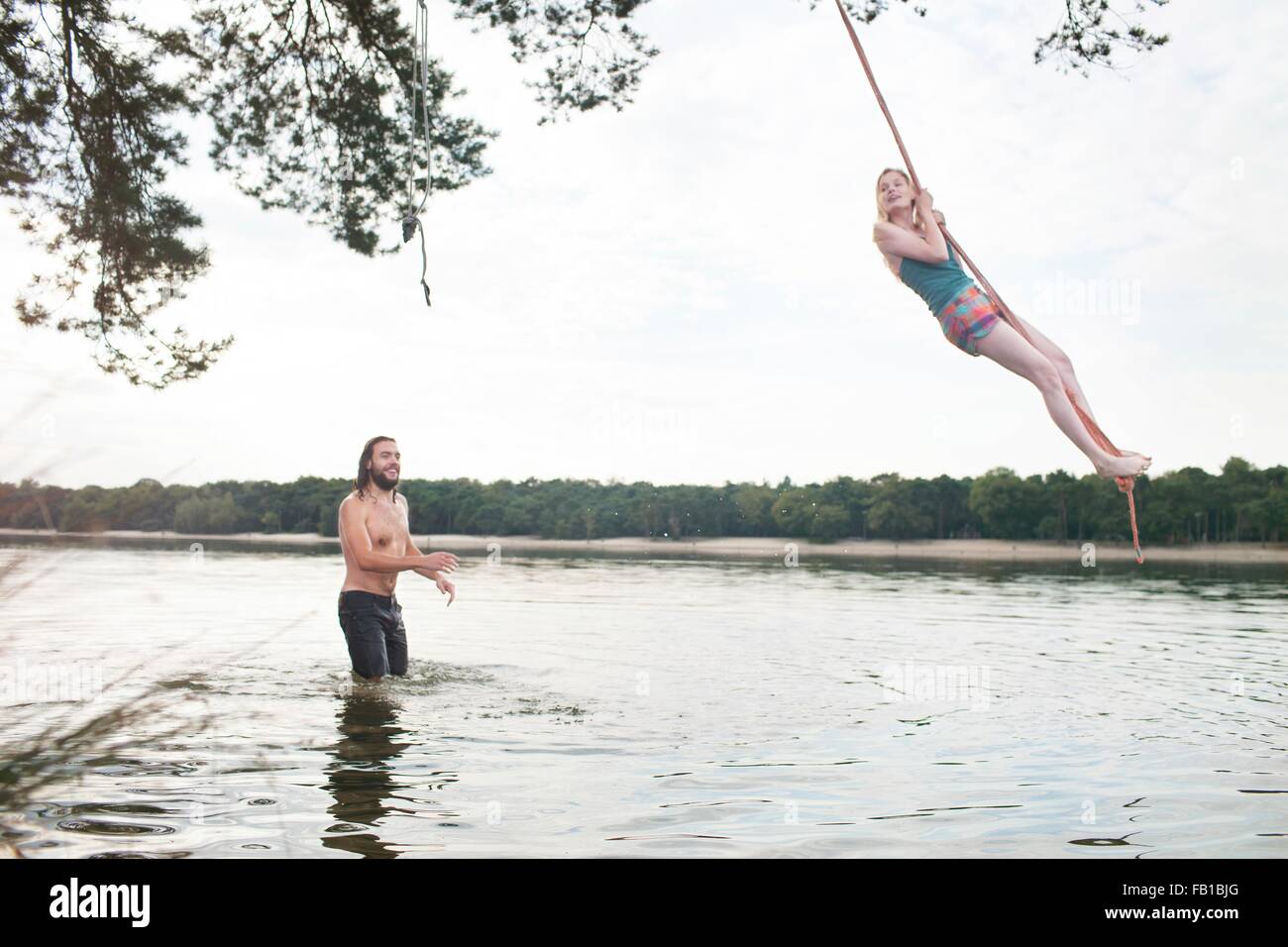 Jeune femme se balancer de corde au-dessus du lac Banque D'Images