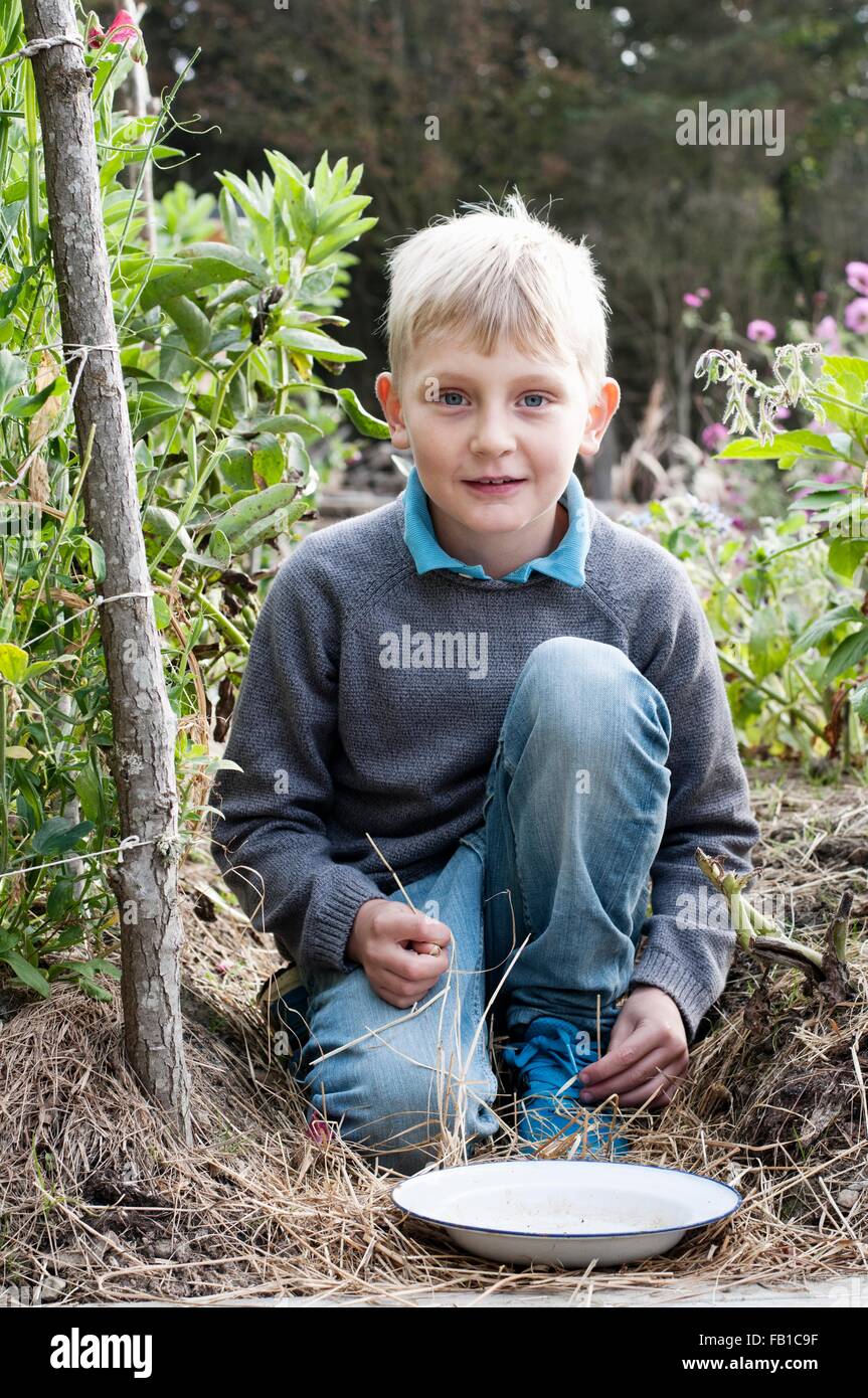 Portrait de garçon à genoux dans le jardin organique Banque D'Images