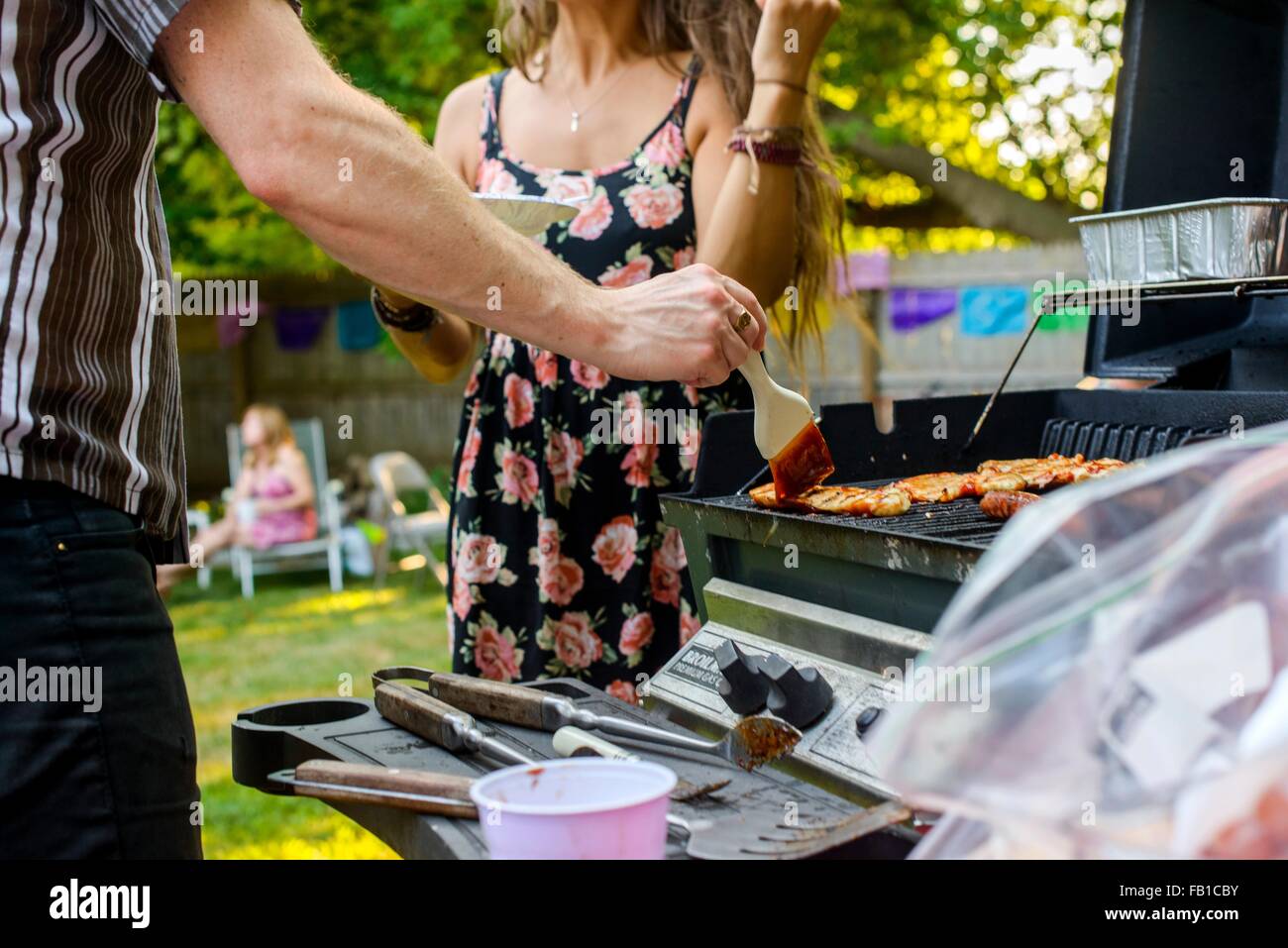 Cropped shot of mid adult man brushing à la sauce barbecue grill Banque D'Images