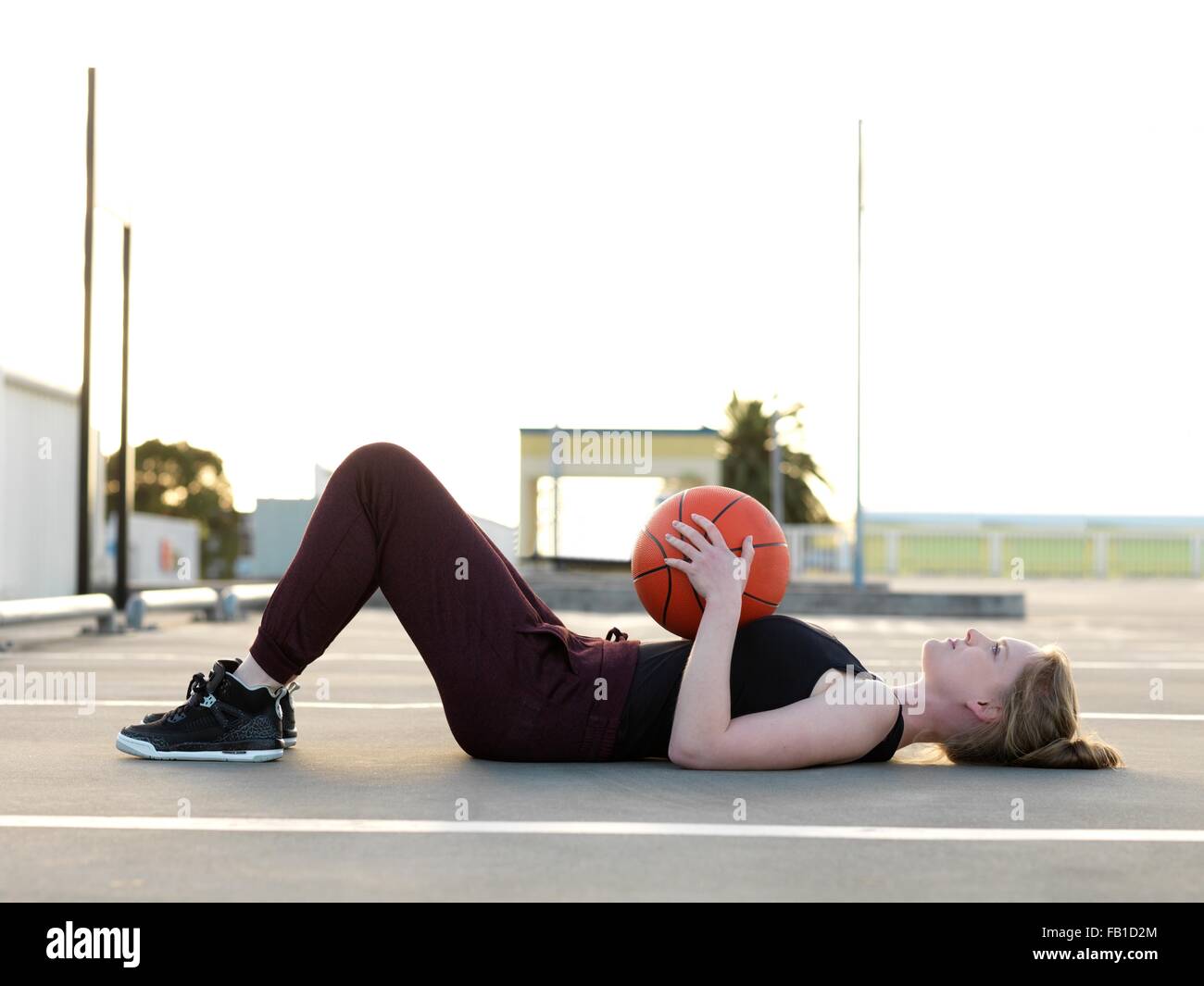 Jeune joueur de basket-ball féminin allongée sur le dos en faisant une pause Banque D'Images