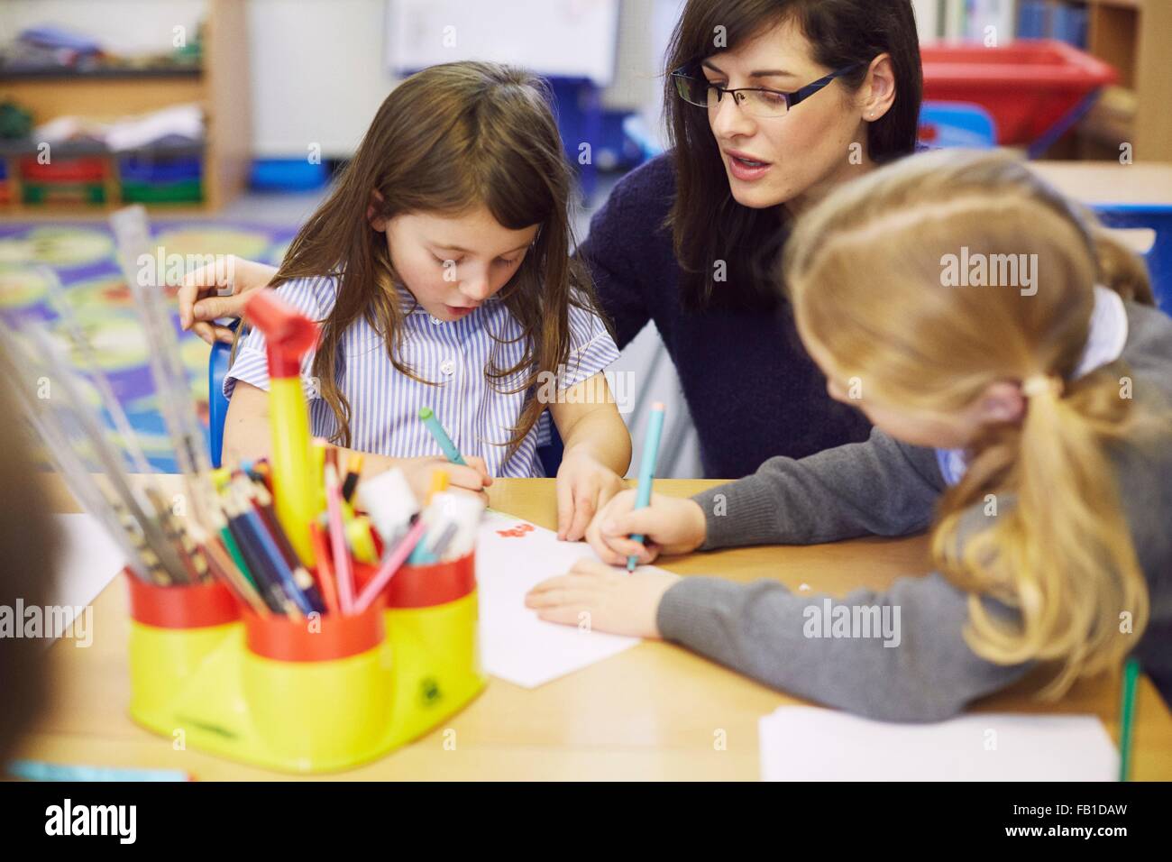 Les filles et le dessin à l'enseignant en salle de classe de l'école élémentaire 24 Banque D'Images