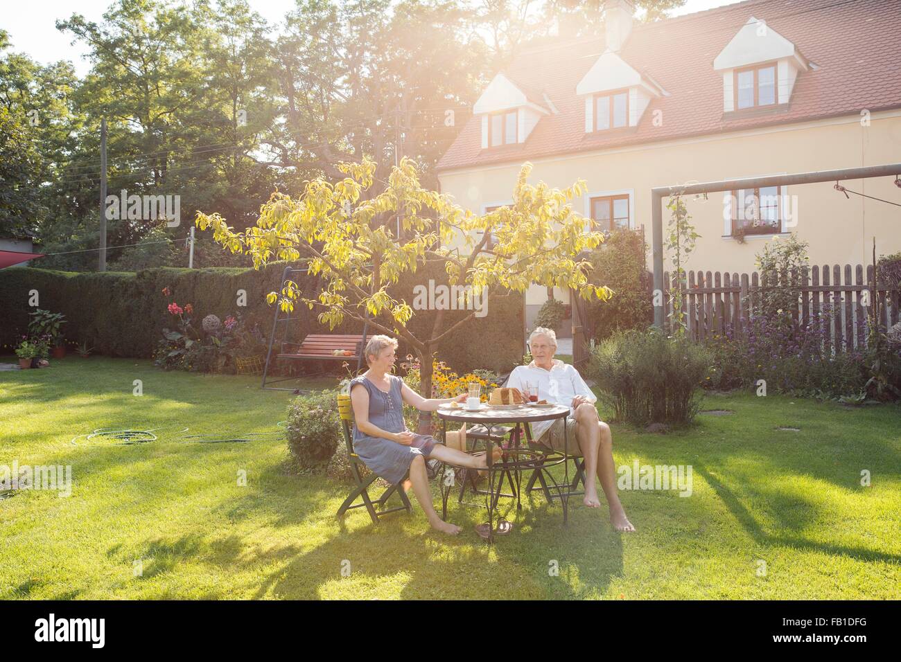 Couple, assis à table dans le jardin, profiter de verre Banque D'Images