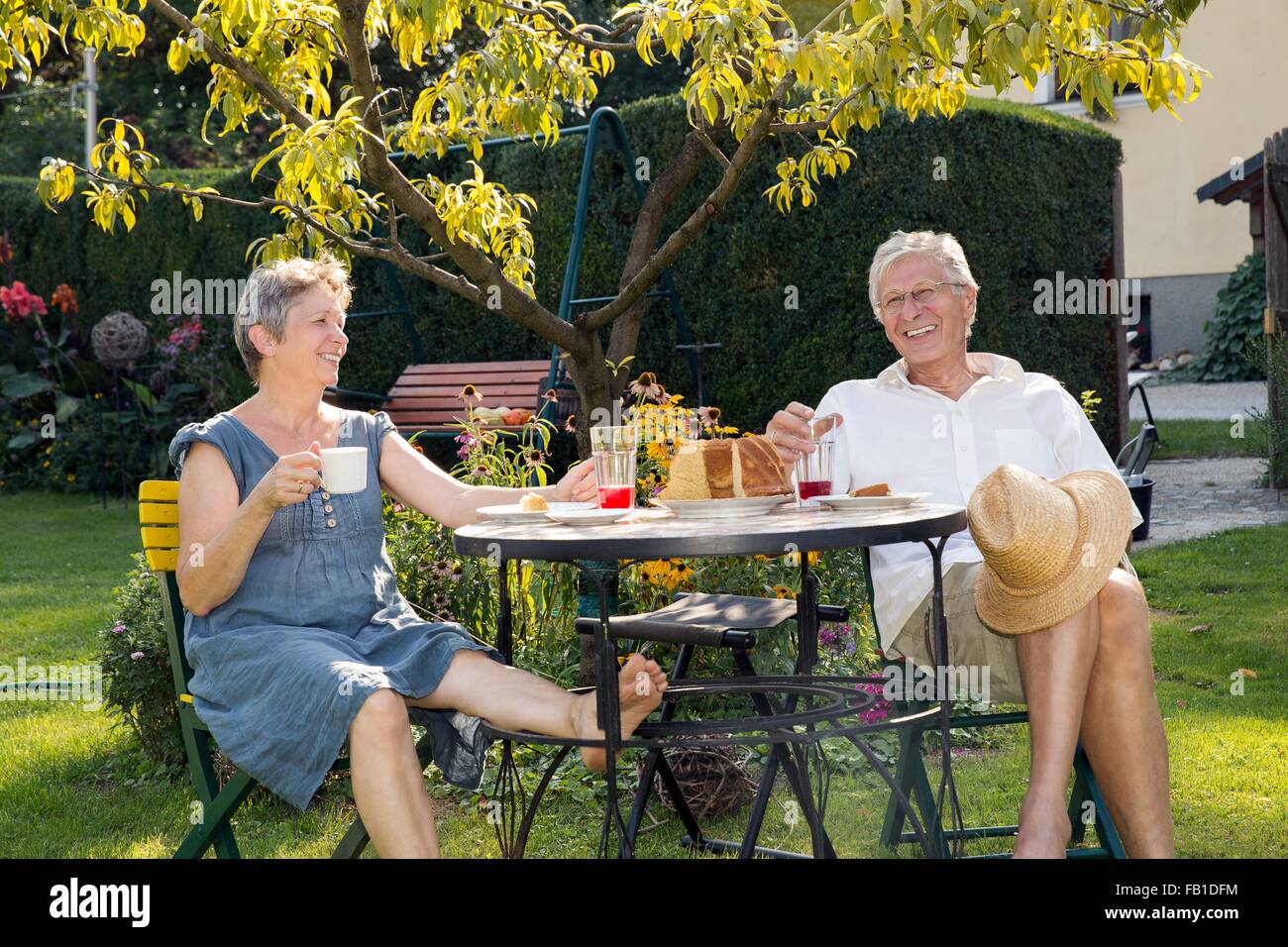 Couple, assis à table dans le jardin, profiter de verre Banque D'Images