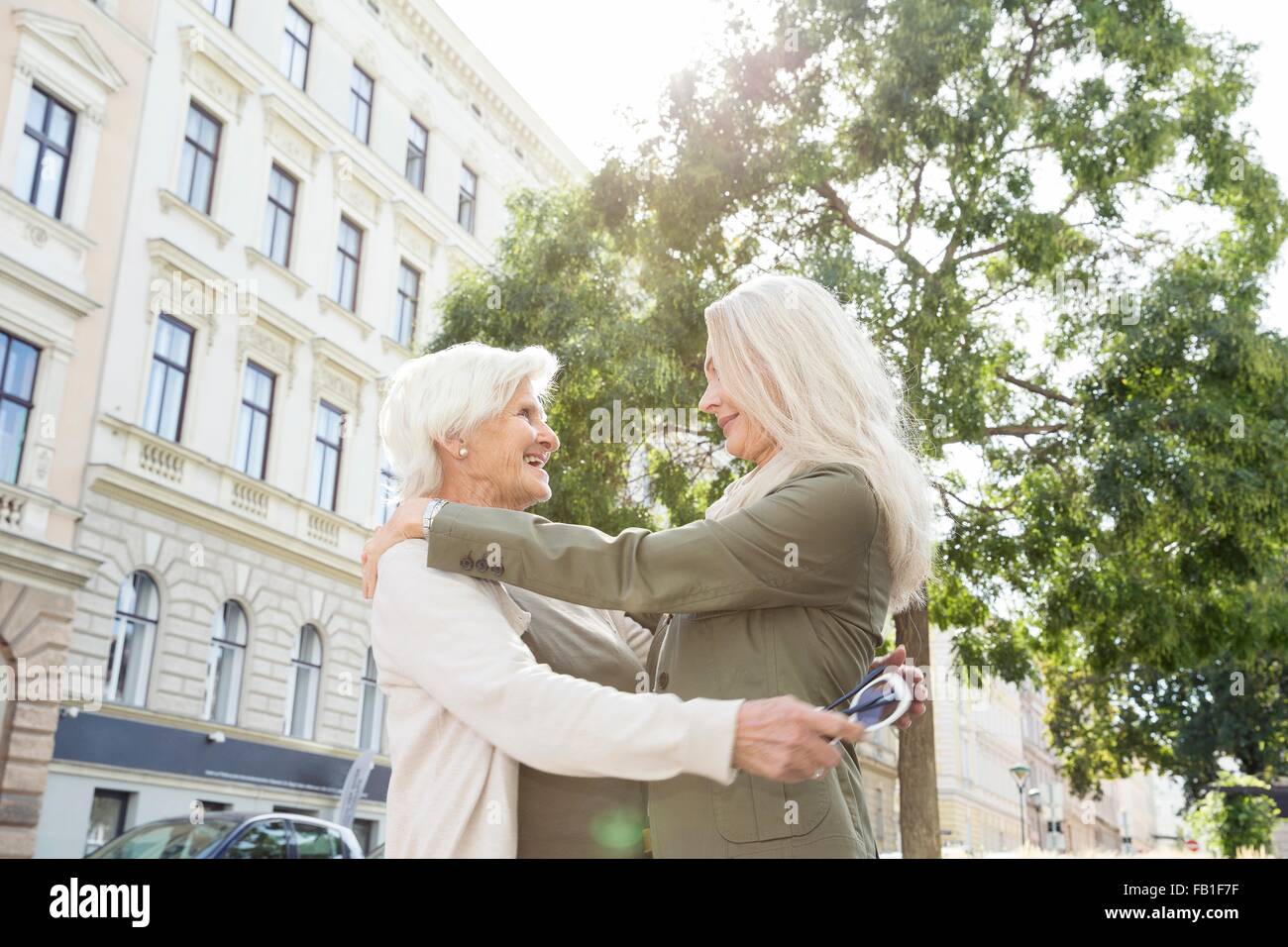 Mother and Daughter hugging in street, smiling Banque D'Images
