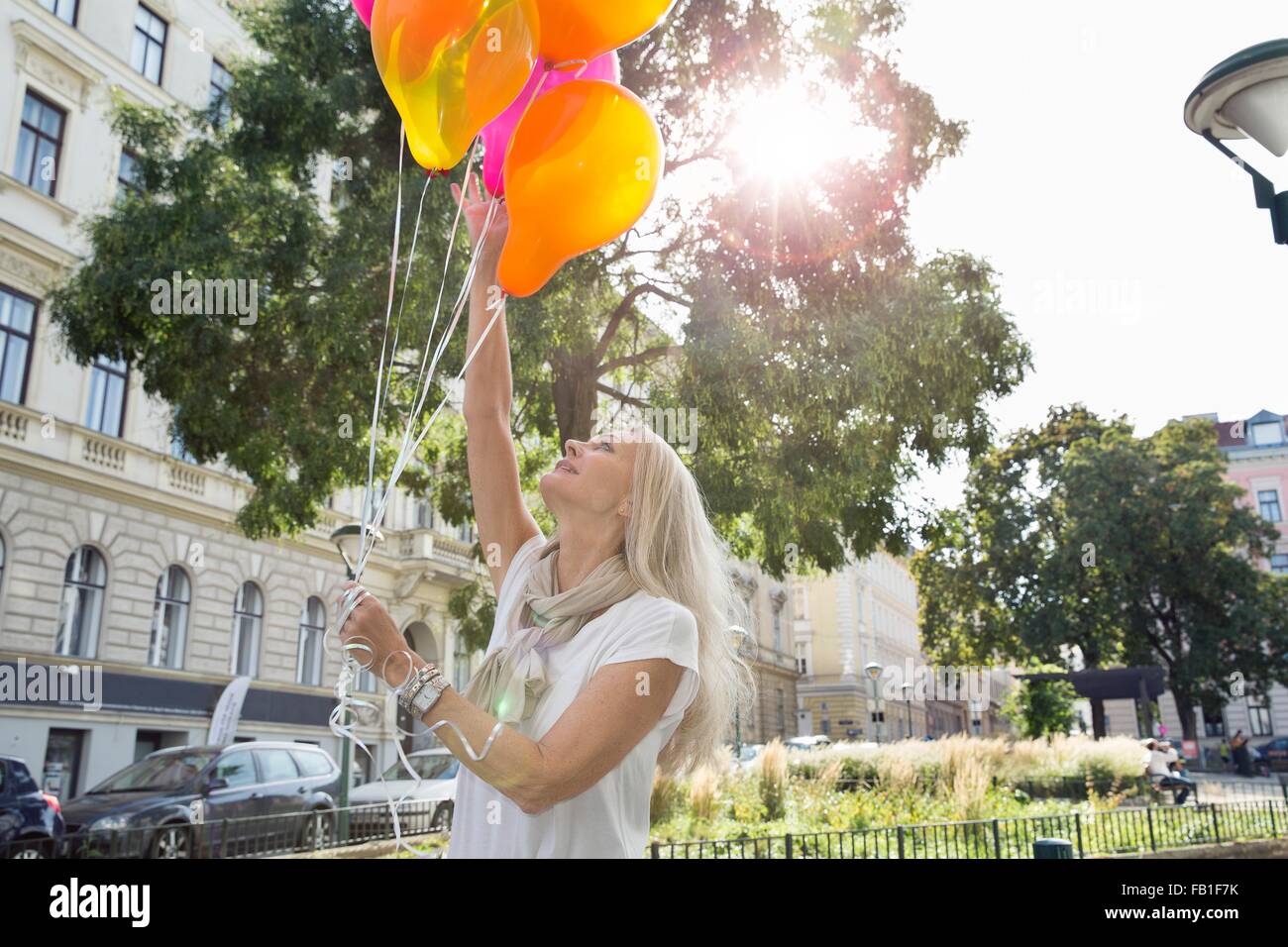 Femme mature, à l'extérieur, holding bunch of balloons Banque D'Images