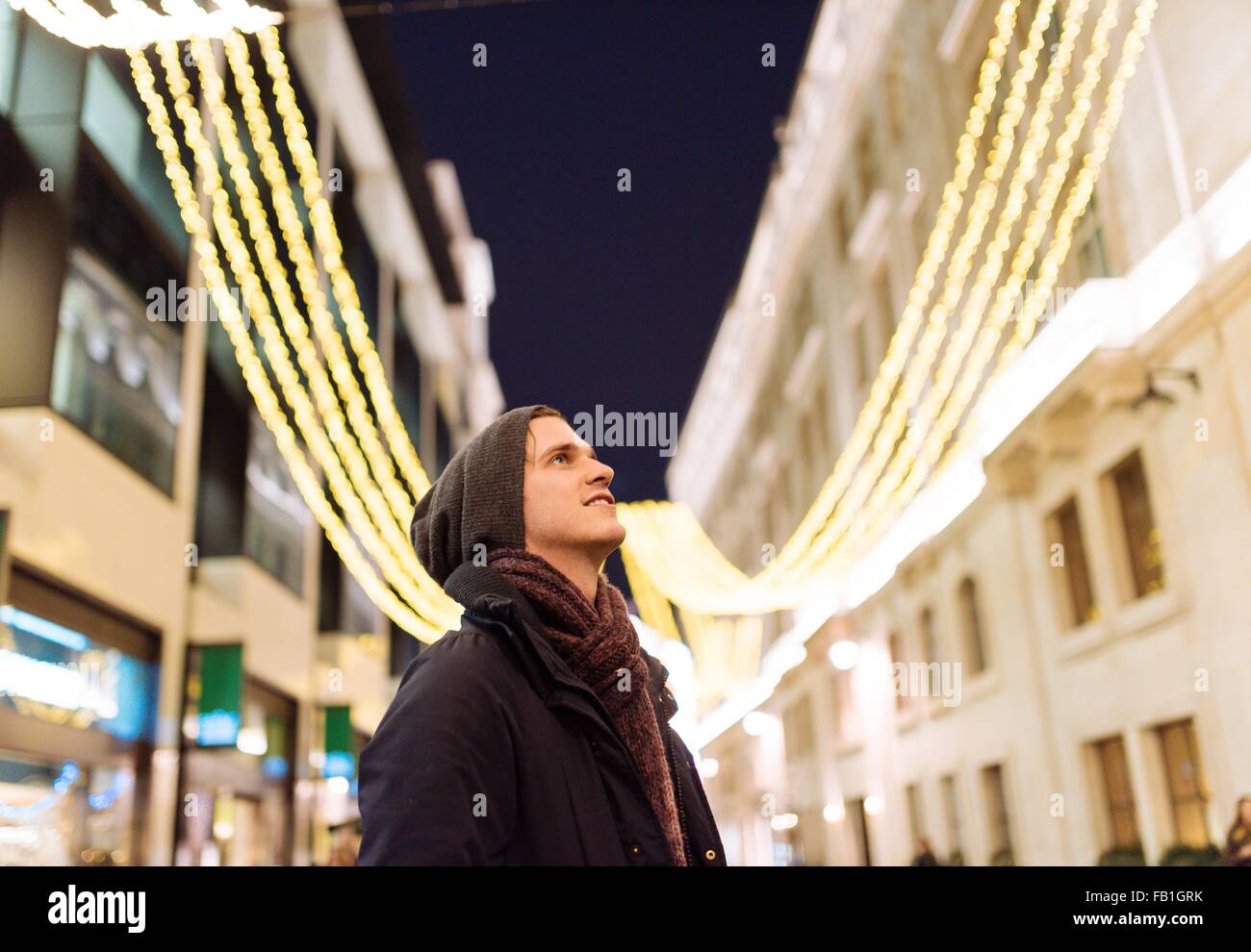 Jeune homme à la recherche jusqu'à Noël lumières, London, UK Banque D'Images