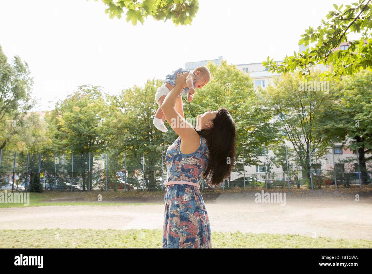 Grand-mère holding up baby granddaughter in park Banque D'Images