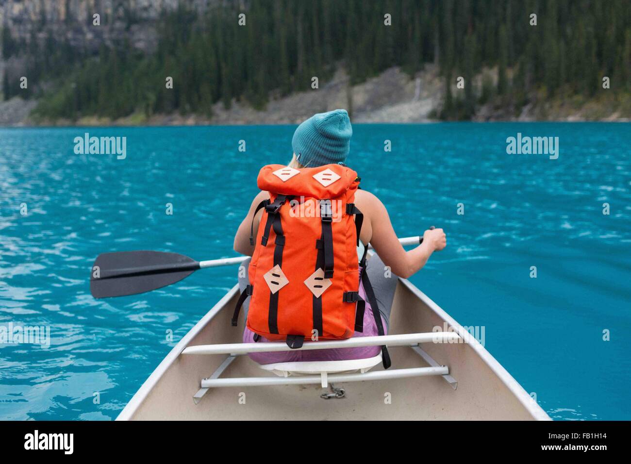 Vue arrière du Mid adult woman avec sac à dos de couleur orange paddling canoe, lac Moraine, Banff National Park, Alberta Canada Banque D'Images