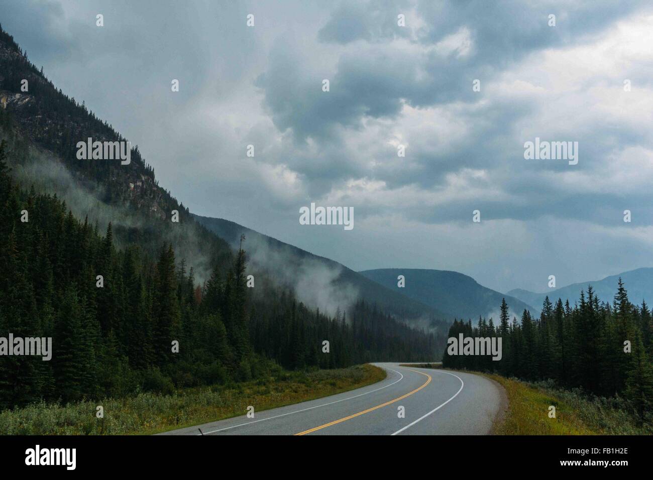 Perspective de diminution de la route ouverte vide et misty mountain range, lac Moraine, Banff National Park, Alberta Canada Banque D'Images