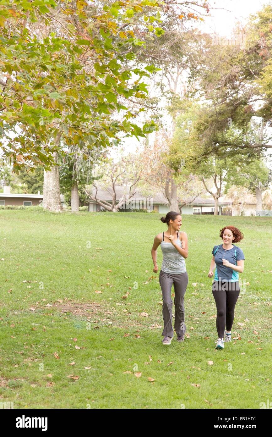 Vue avant pleine longueur de femmes portant des vêtements de sport running on grass Banque D'Images