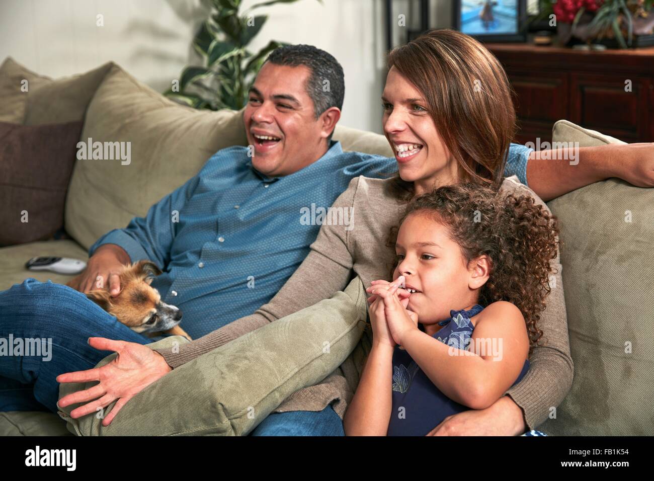 Family côte à côte sur un canapé à l'écart smiling Banque D'Images
