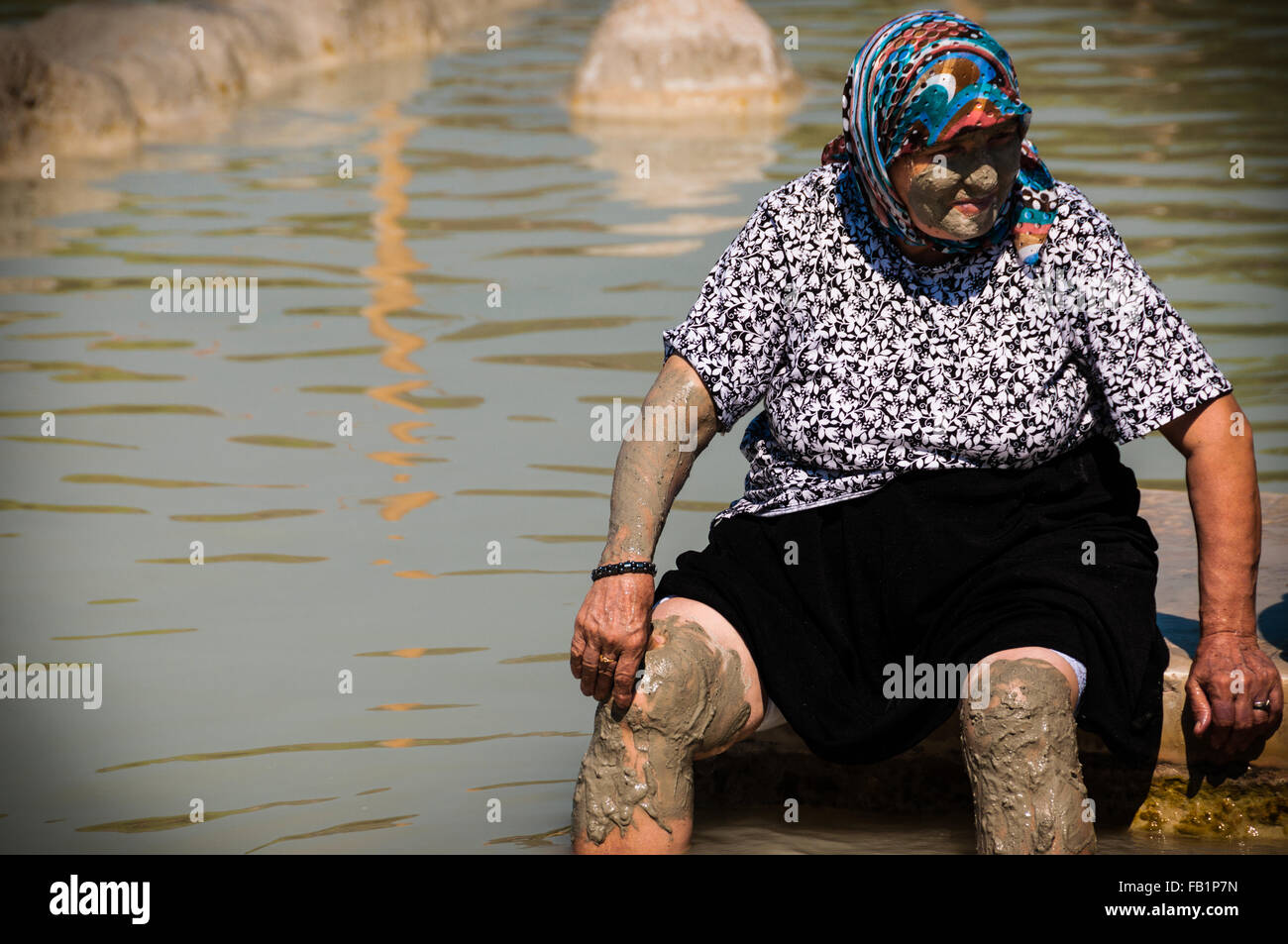 Vieille femme turque avec la boue en face et d'écharpe sur la tête assis à hot spring Banque D'Images