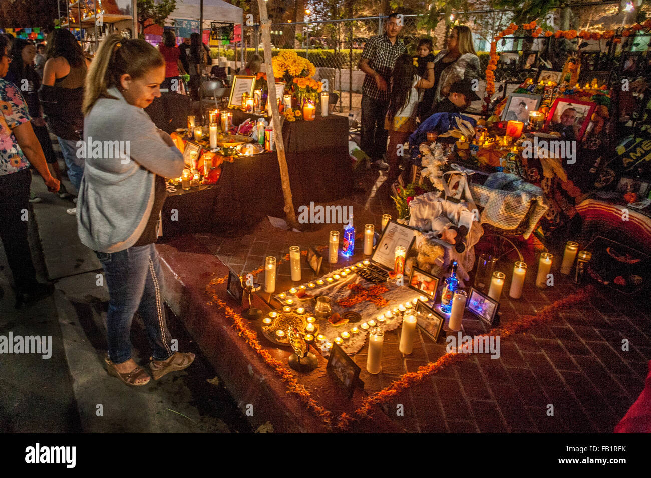 Éclairé par des bougies votives, un autel en l'honneur d'un membre de la famille décédé est exposé sur le Jour des Morts mexicain ou Dia de muertos dans un quartier hispanique à Santa Ana, CA. Remarque portrait encadré en premier plan à gauche et à l'inhumation en croix centre. L'h Banque D'Images