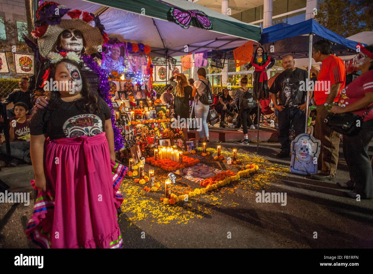 Éclairé par des bougies votives, un autel en l'honneur d'un membre de la famille décédé est exposé sur le Jour des Morts mexicain ou Dia de muertos dans un quartier hispanique à Santa Ana, CA. Remarque portrait encadré de la victime en arrière-plan, la mère et la fille je Banque D'Images