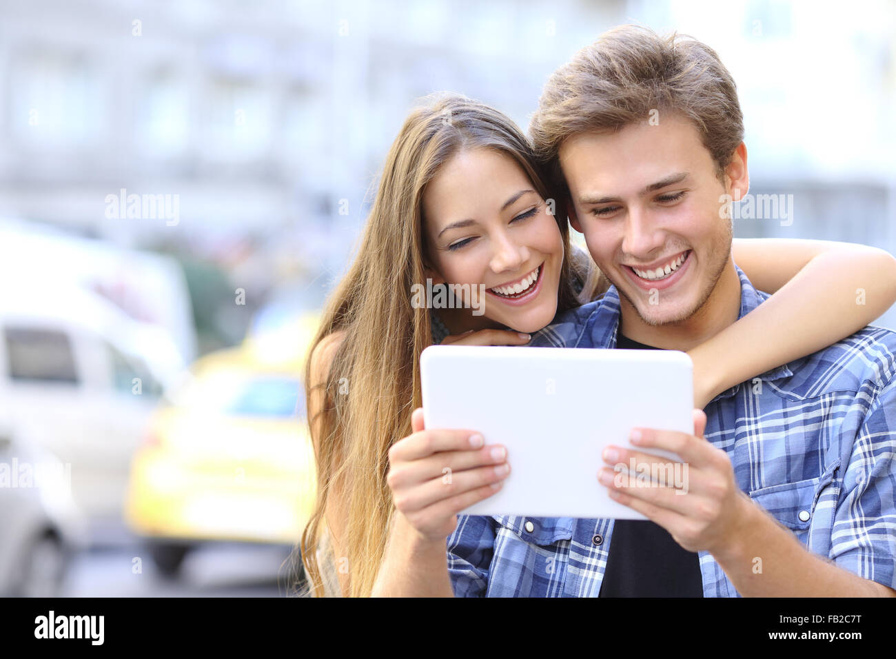 Couple heureux ou friends hugging et partage une tablette dans la rue Banque D'Images