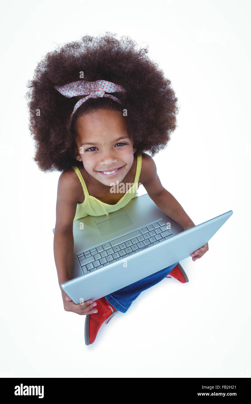 Cute girl sitting on floor using laptop and smiling at camera Banque D'Images