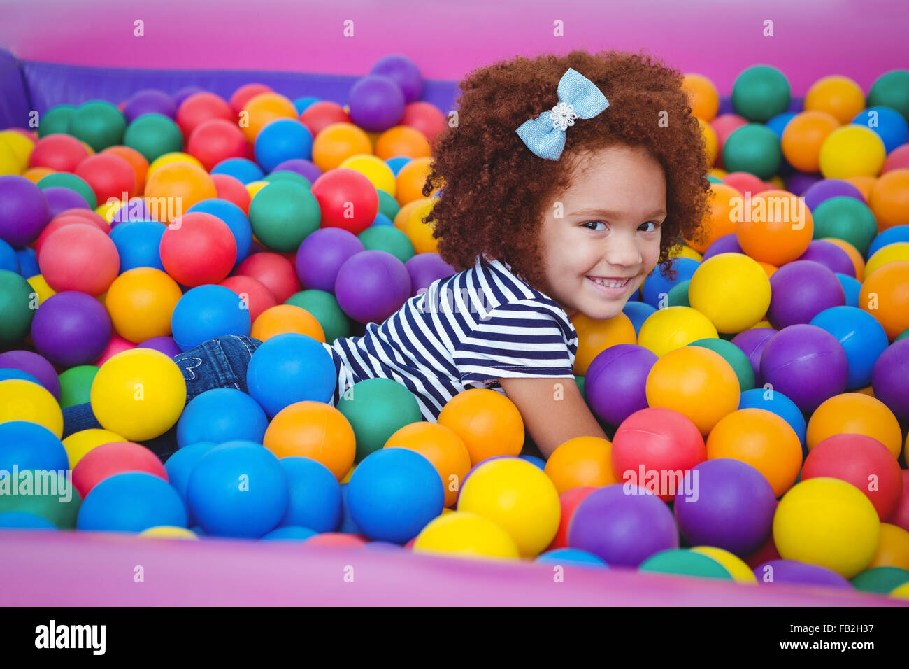 Cute smiling girl in sponge ball pool Banque D'Images