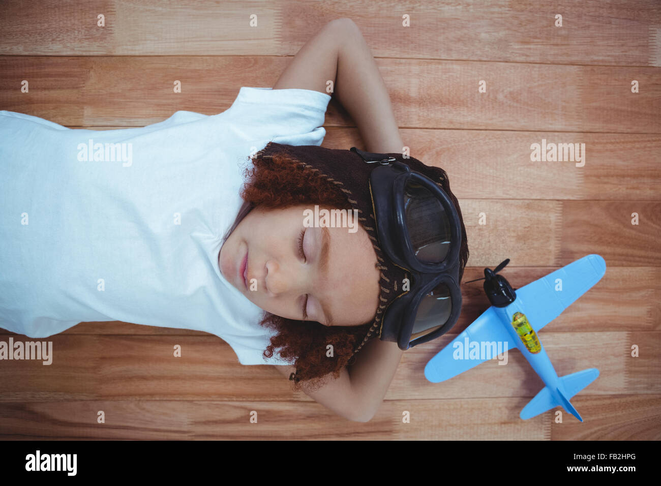 Smiling girl dormir sur le plancher portant des lunettes aviator et hat Banque D'Images