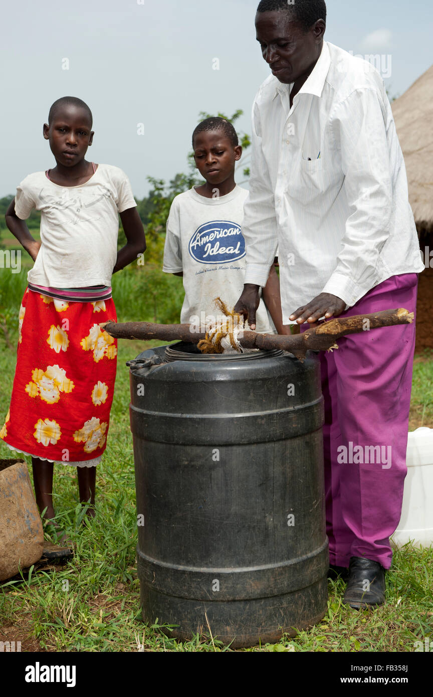 Des agriculteurs en engrais liquide du fumier de vaches trempées dans le baril rempli d'eau. Au Kenya. Banque D'Images