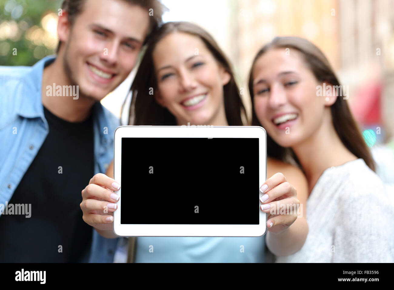 Trois amis heureux montrant un écran de tablette dans la rue Banque D'Images