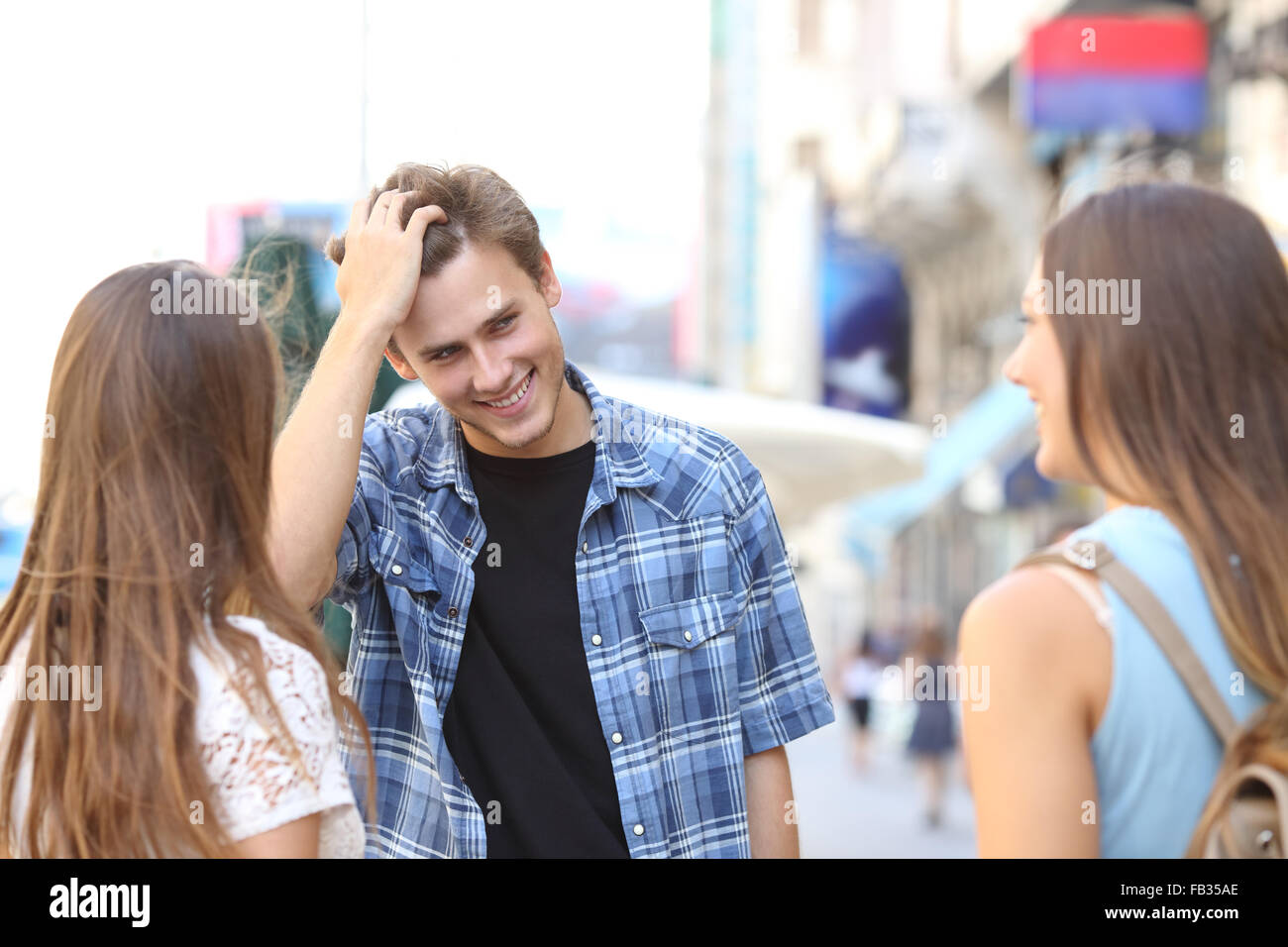 Beau jeune homme flirter avec deux filles dans la rue Banque D'Images