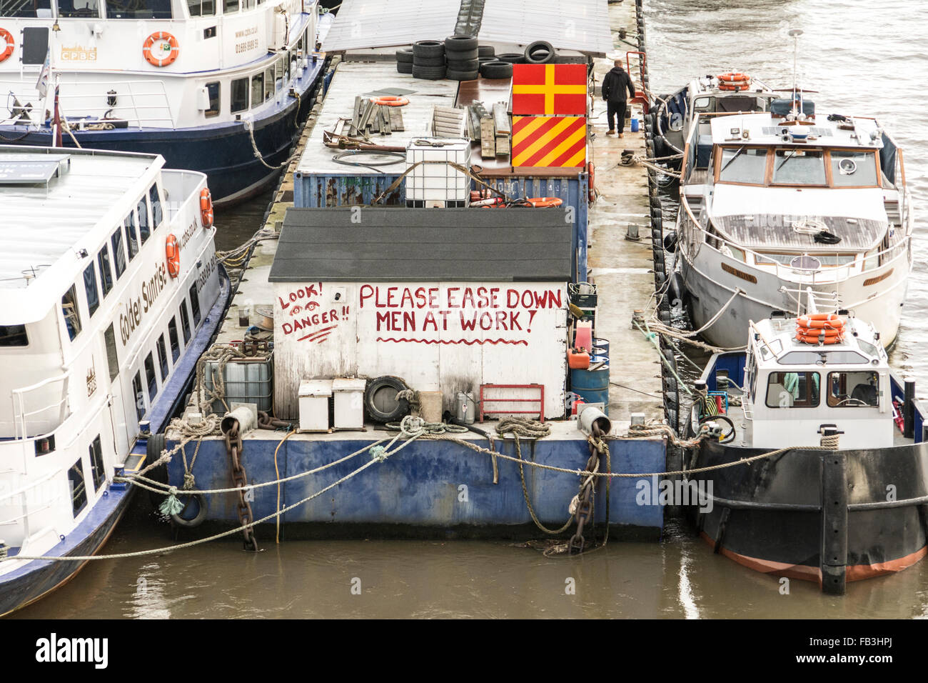 Londres, Angleterre, Royaume-Uni. Avis sur une barge dans la Tamise - Veuillez Facilité vers le bas - l'homme au travail Banque D'Images