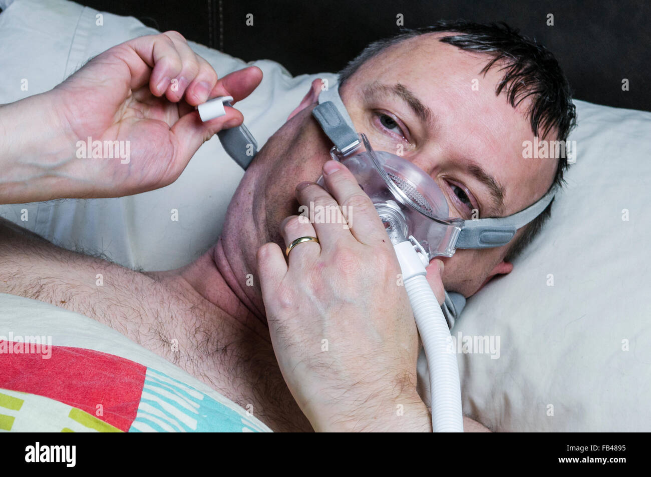 Un excès d'âge moyen, l'homme ajuste un masque CPAP avant de dormir Banque D'Images