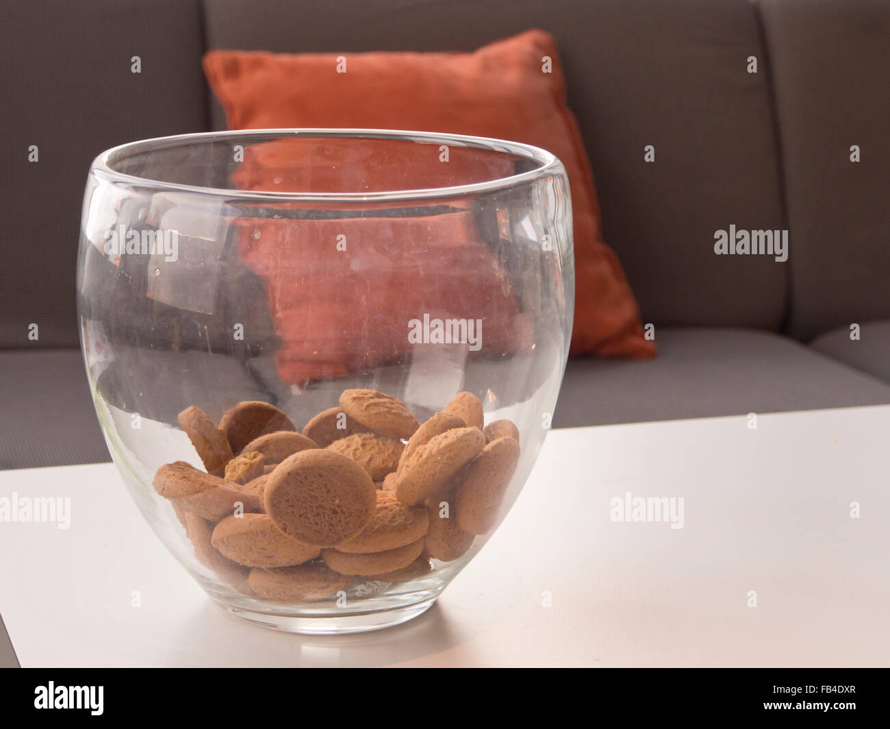 Les écrous de gingembre dans un grand bol en verre sur une table, canapé avec coussin derrière orange Banque D'Images