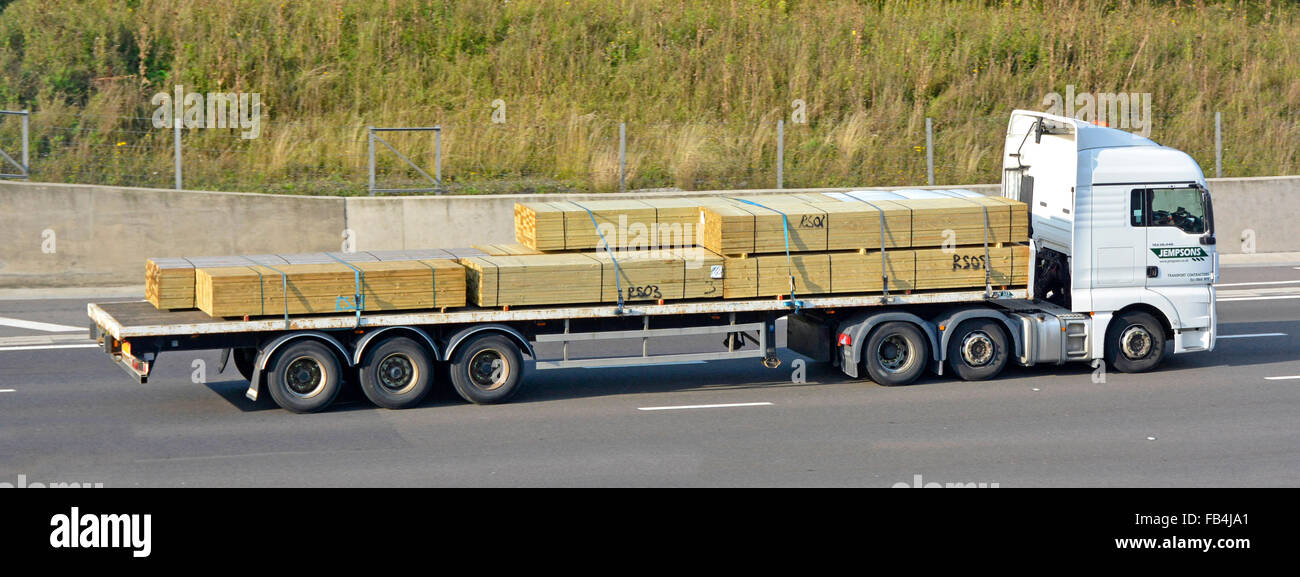 Vue latérale du secteur du transport de camions de camion hgv avec charge de remorque articulée à plat articulée en bois de construction groupé conduisant sur l'autoroute UK Banque D'Images