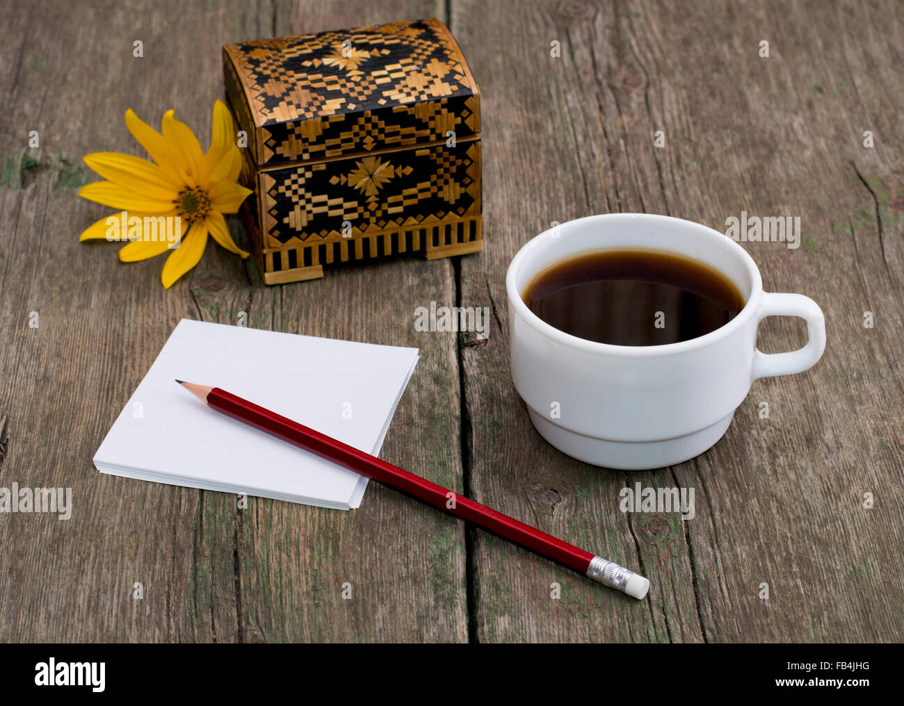 Coffret, café, un crayon de papier et une fleur jaune Banque D'Images