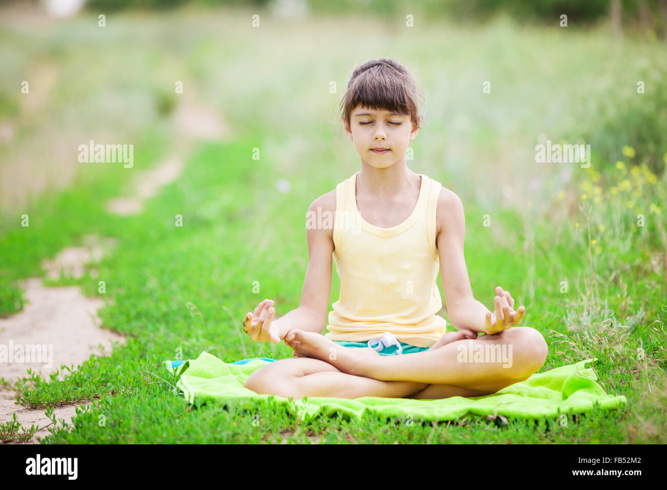Jeune fille se détendre tout en étant assis en position du lotus en plein air Banque D'Images