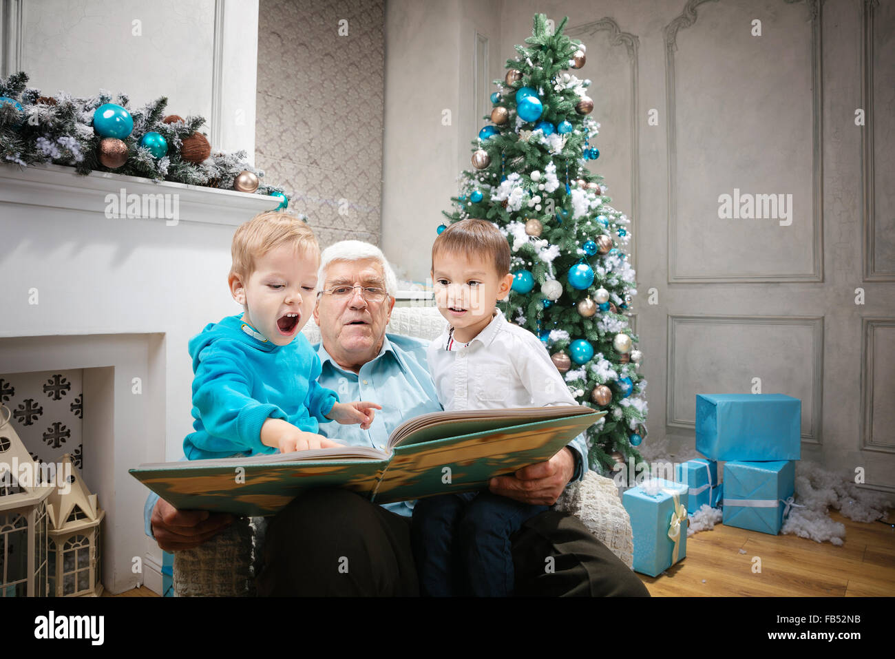 Senior man reading a book pour petits-fils à la veille de Noël Banque D'Images