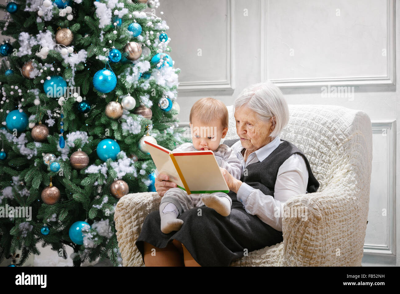 Senior woman lire un livre à son petit-fils à côté d'un arbre de Noël Banque D'Images